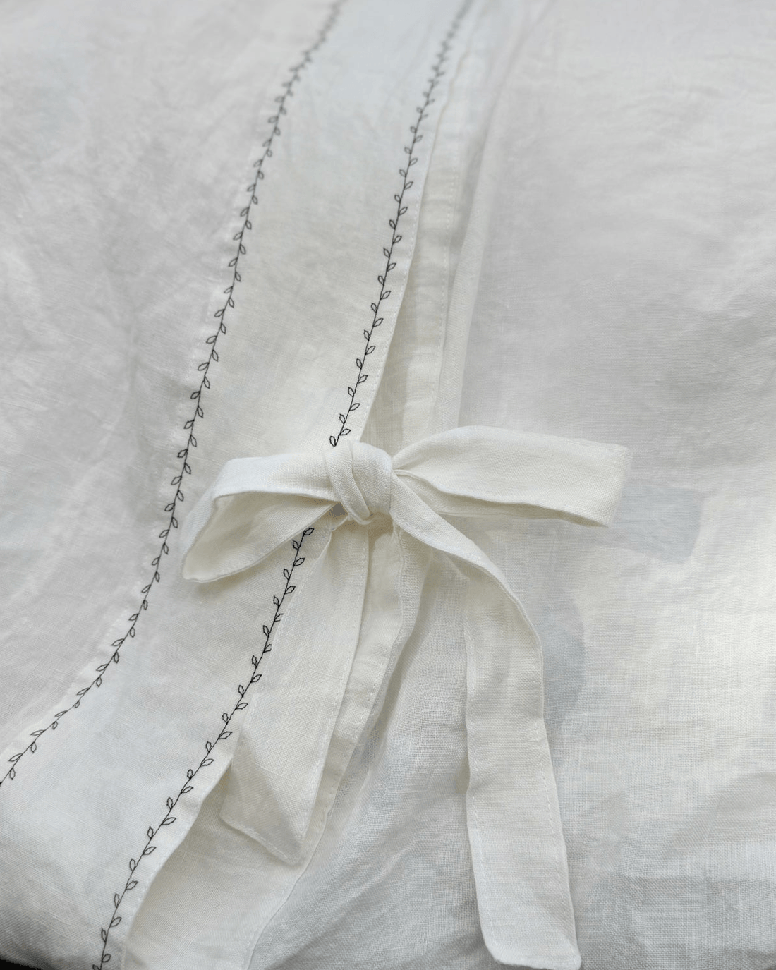 White embroidered linen duvet cover with ribbon tie detail, blog illustration