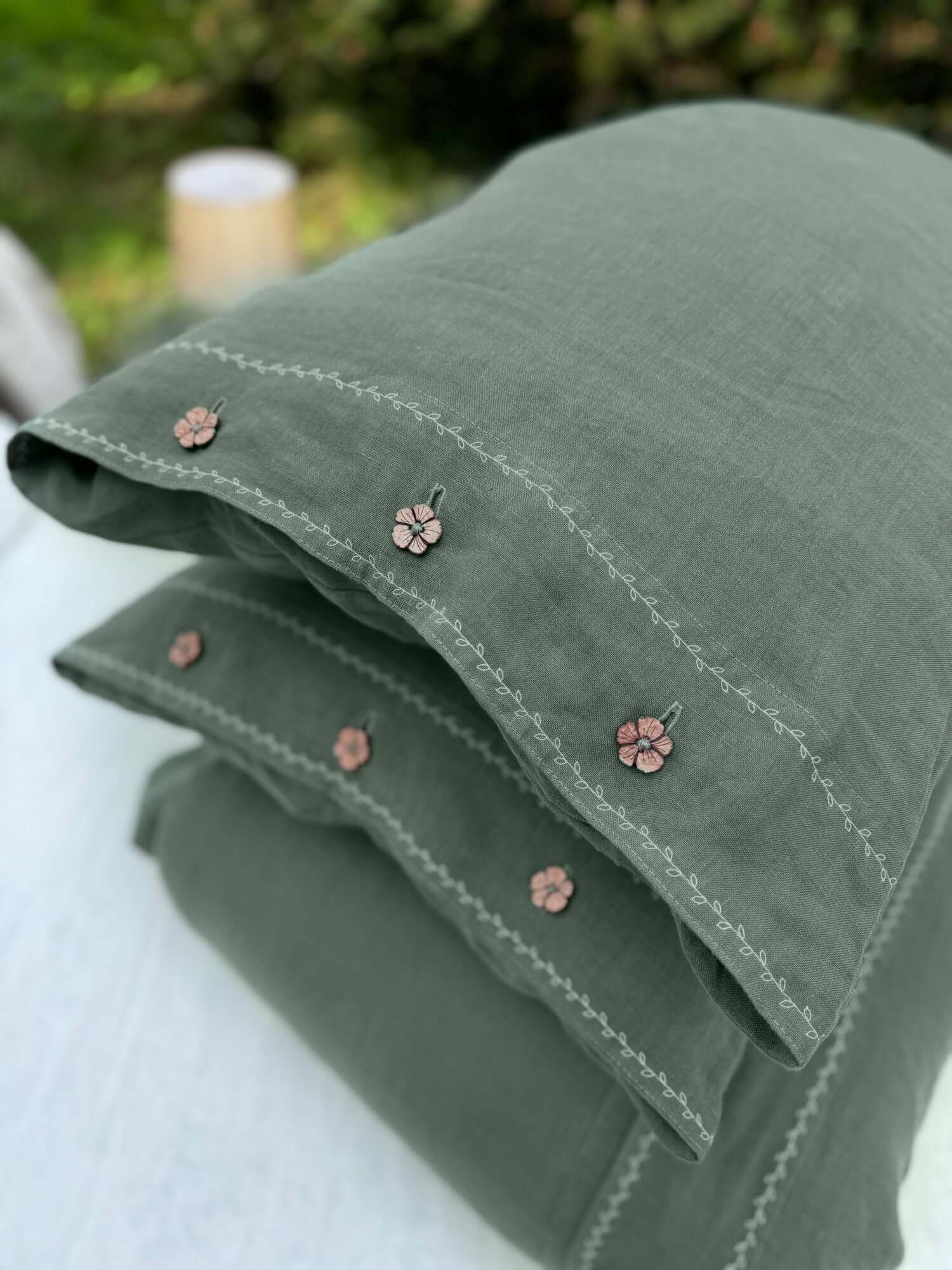 White embroidered linen pillowcase on bed, close-up of white embroidery detail