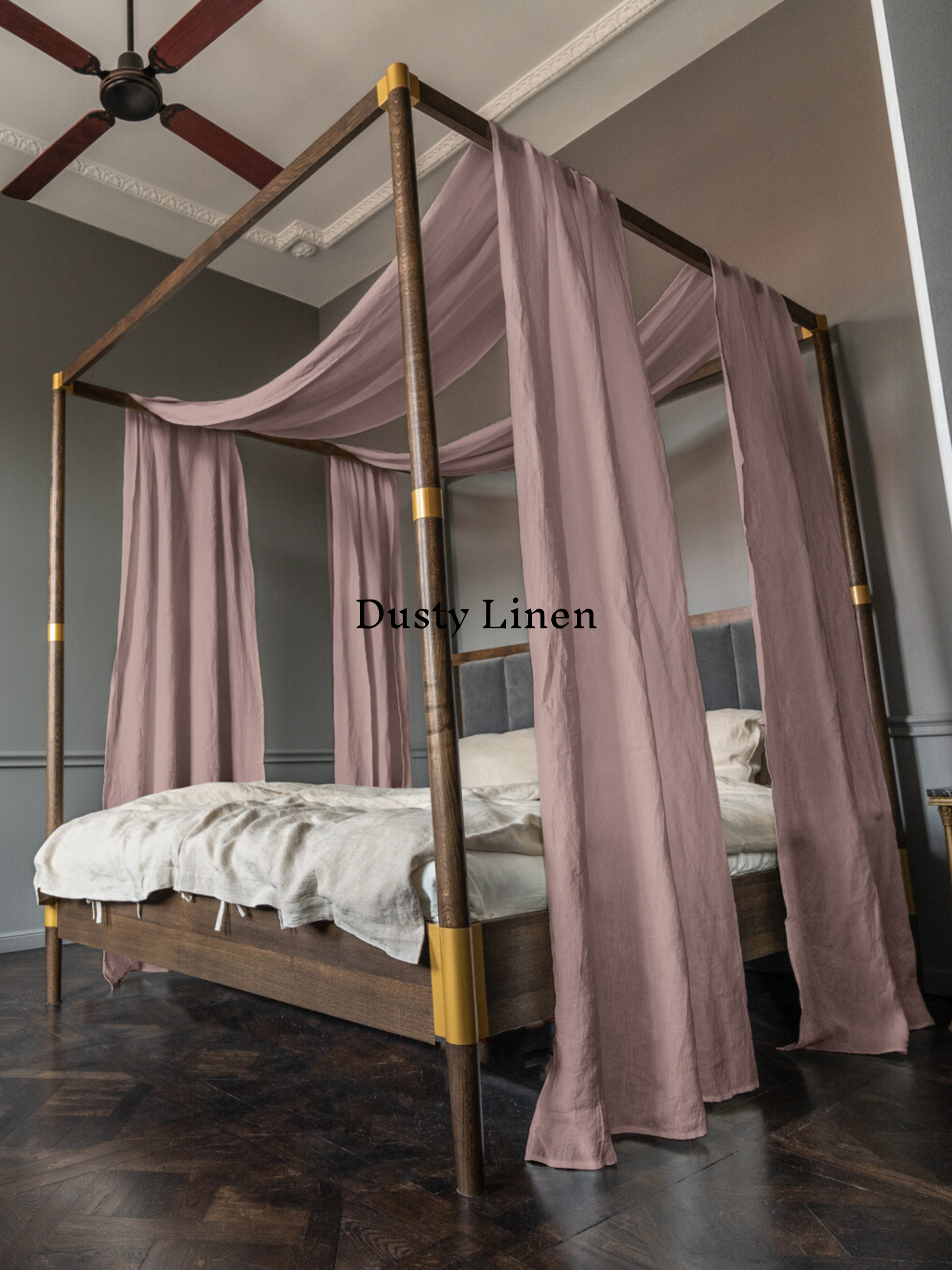 a four poster bed with pink drapes on it