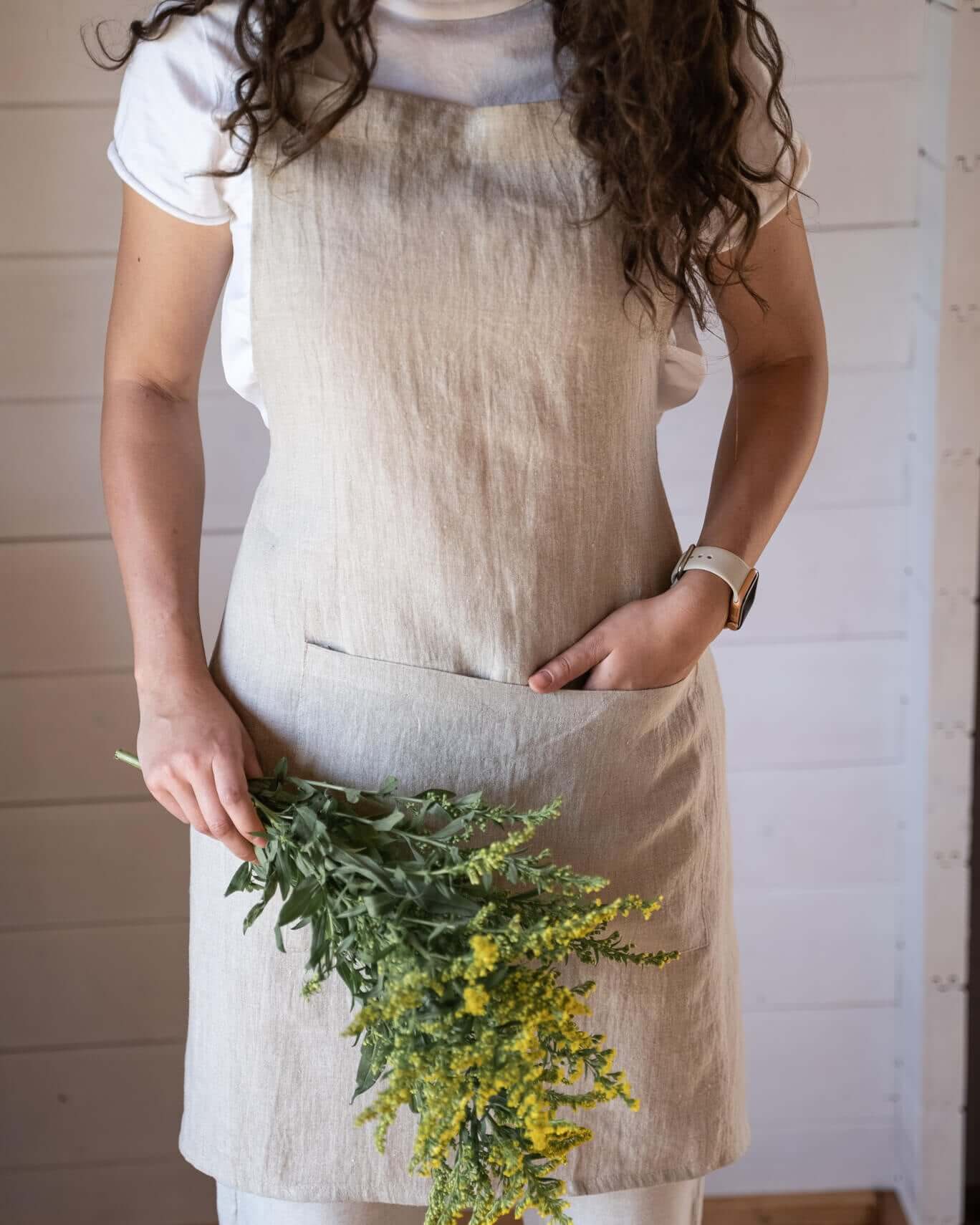 Linen apron worn outdoors with plant styling, front view