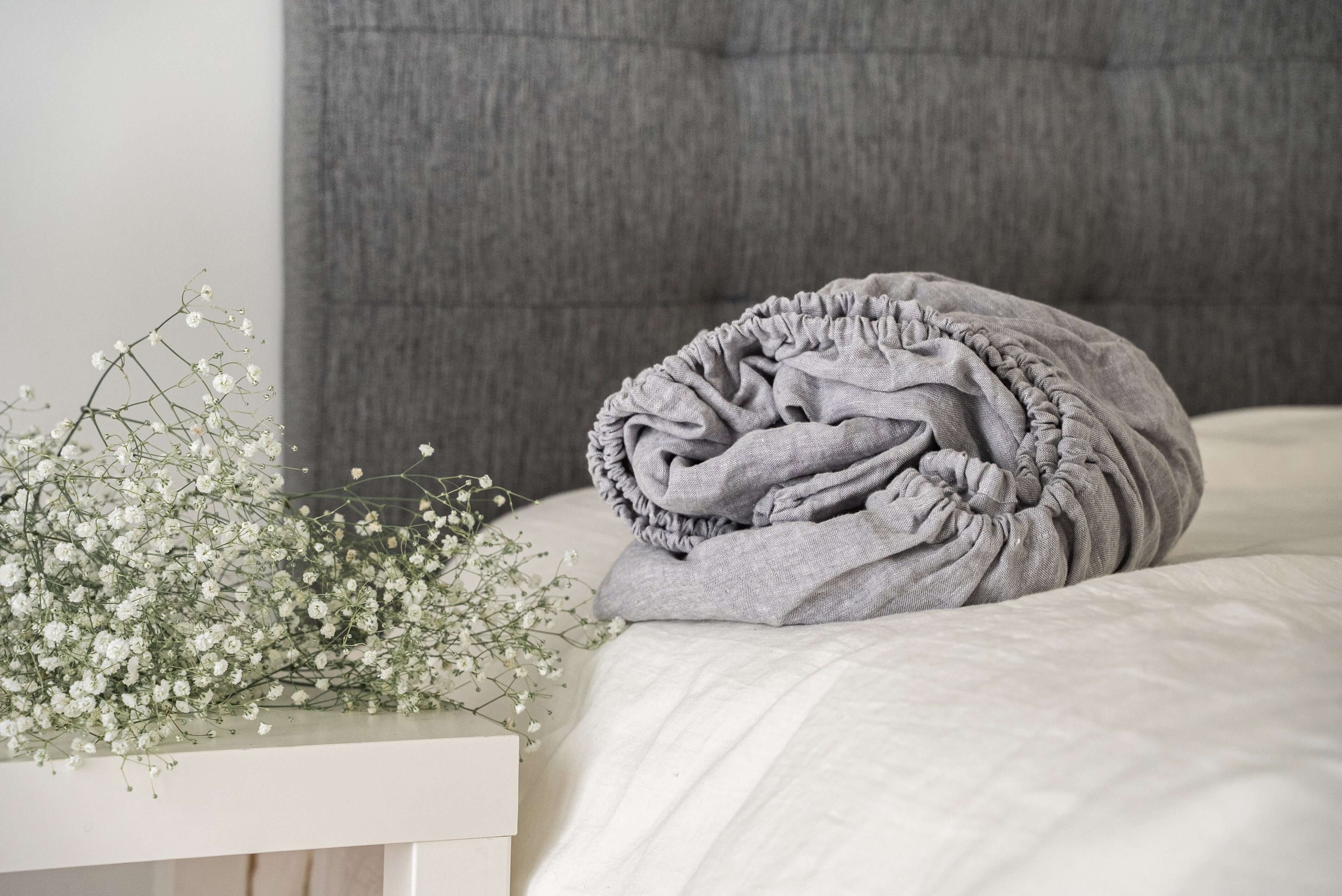 Gray linen pillow and blanket on bed, cozy bedroom styling