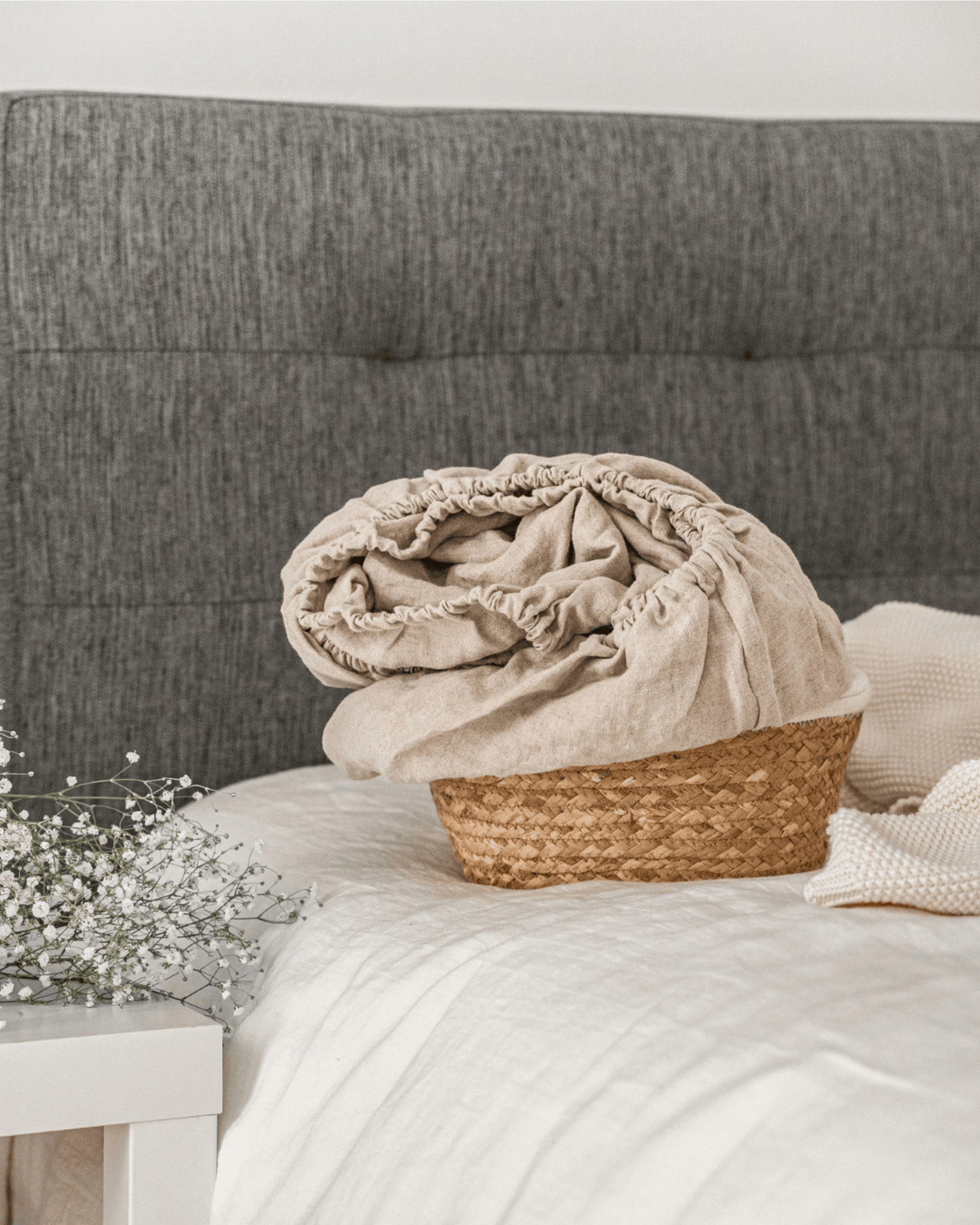 Linen fitted sheet on bed with woven basket and linen blanket