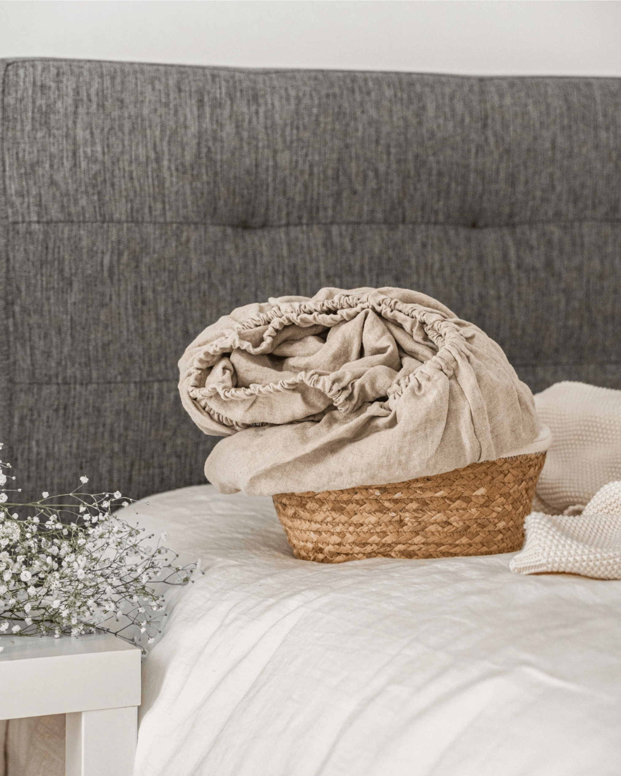 Linen fitted sheet on bed with woven basket and linen blanket