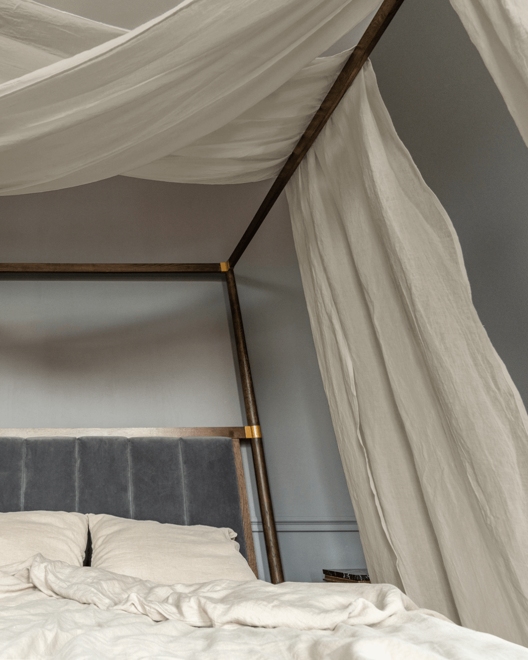 Close-up of linen canopy curtains draped over a bed frame
