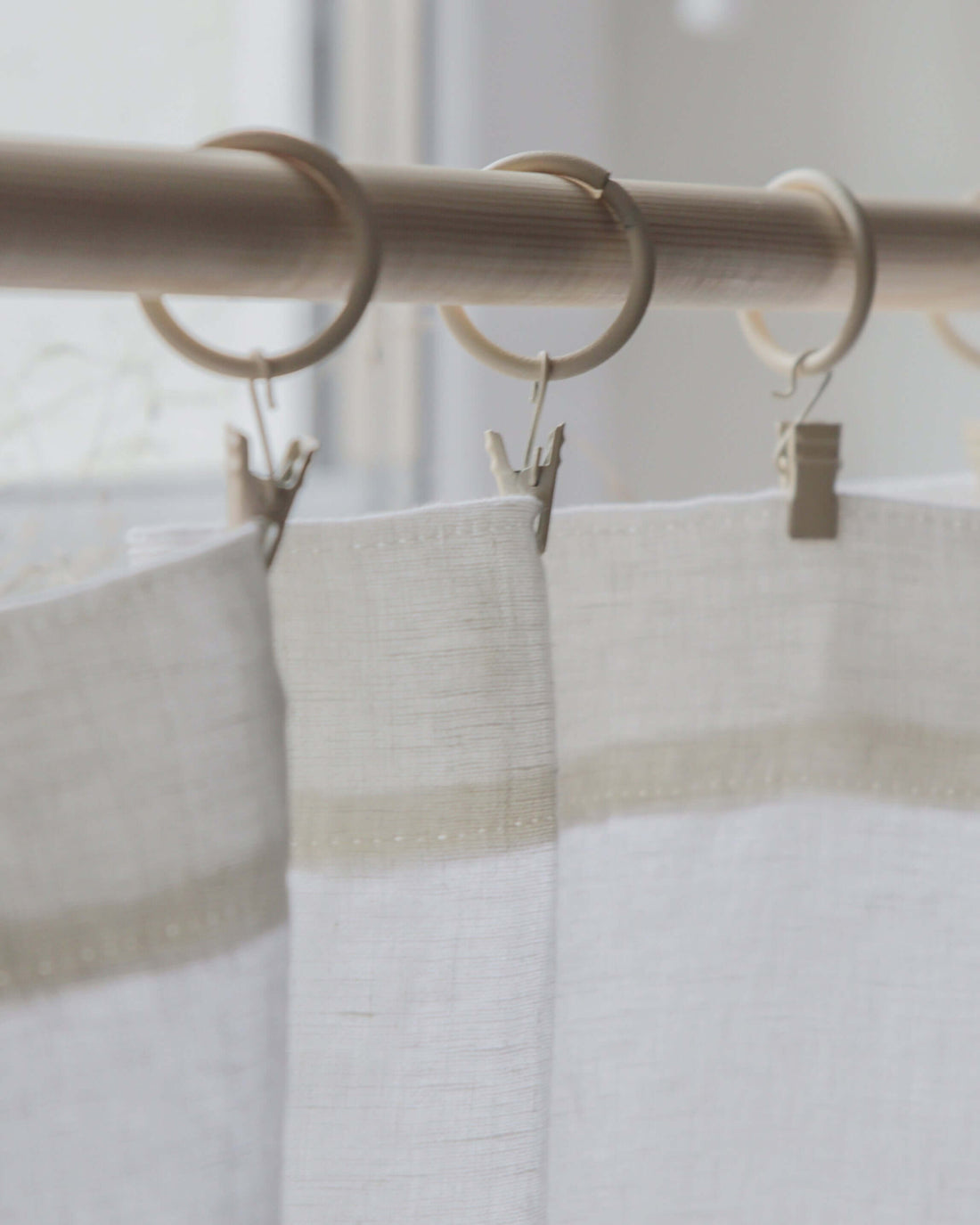 Linen curtain with simple hem hanging from clips on a rod