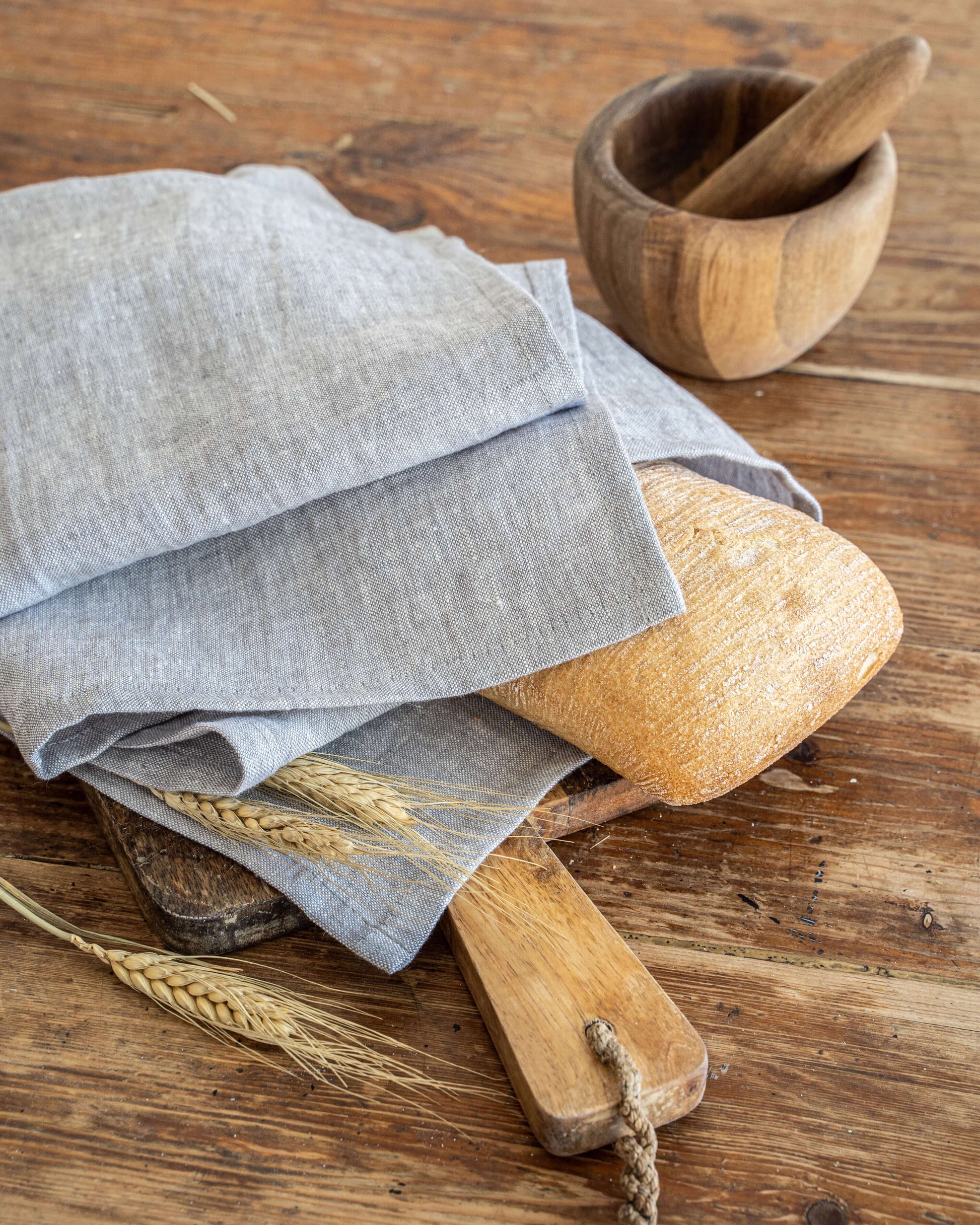 Linen tea towel draped over wooden board with bread