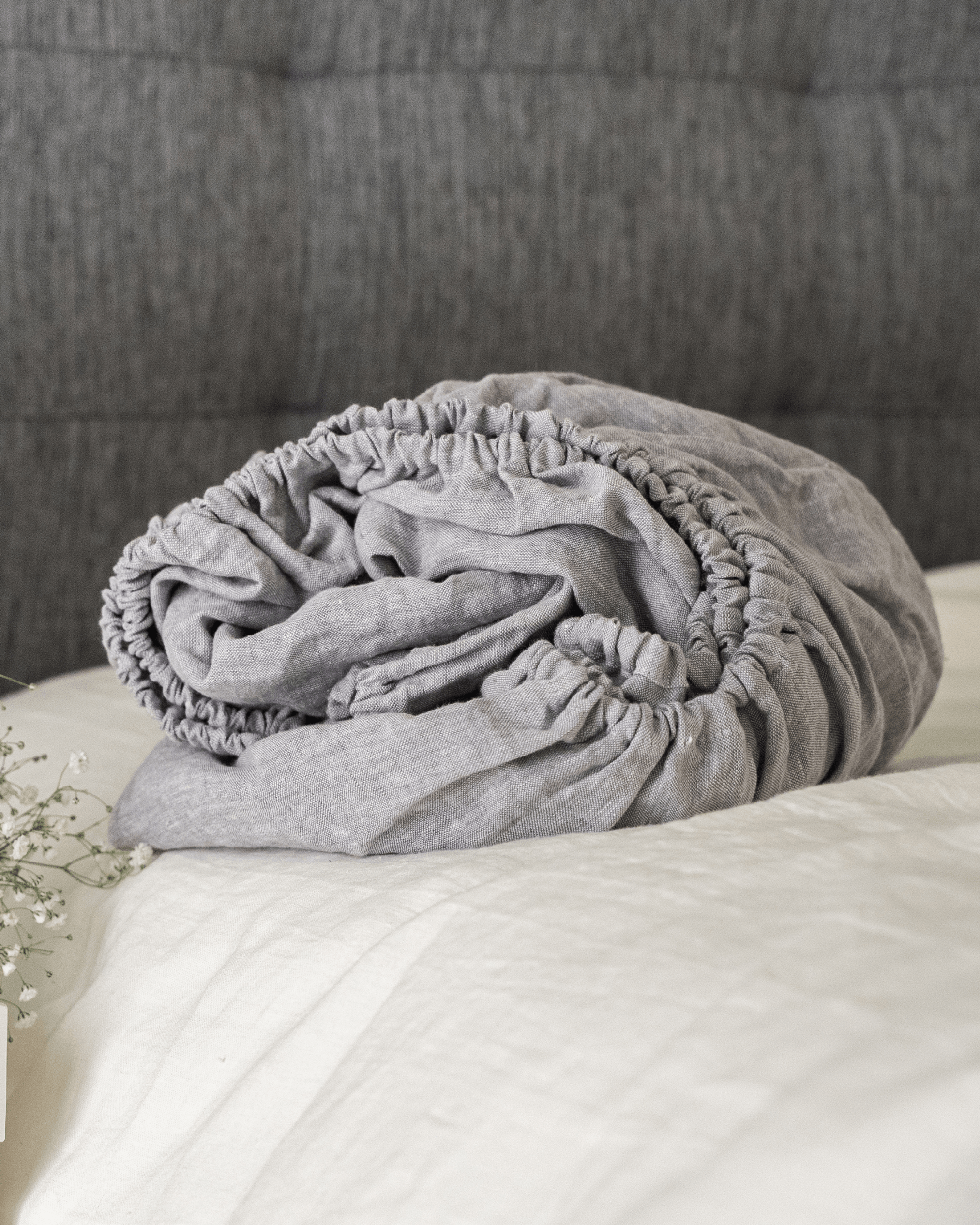 Linen fitted sheet on bed with floral arrangement, lifestyle bedroom photo