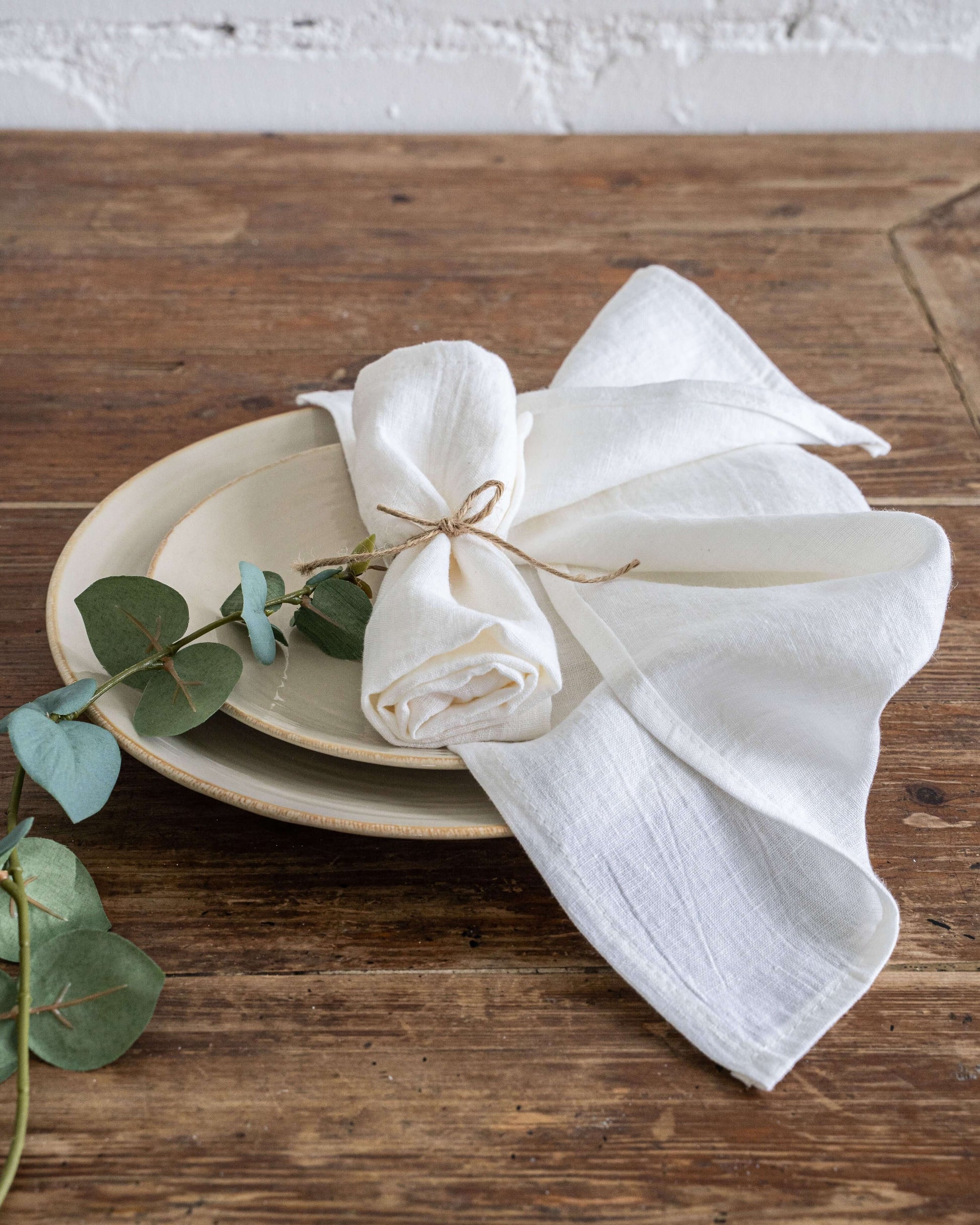 Off white linen napkin softly folded beside a plate and cutlery