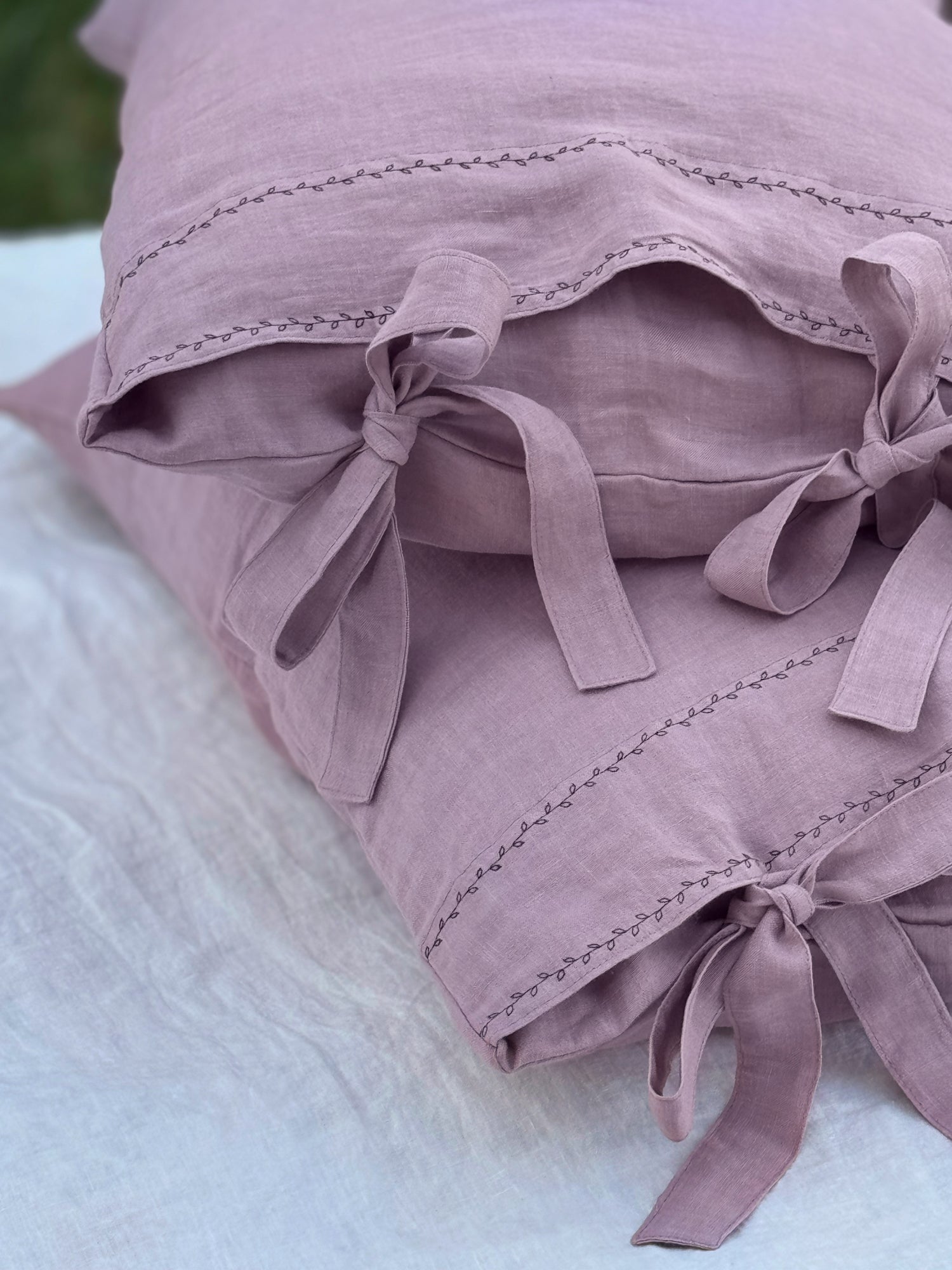 Black embroidered linen pillowcase in dusty rose, close-up detail