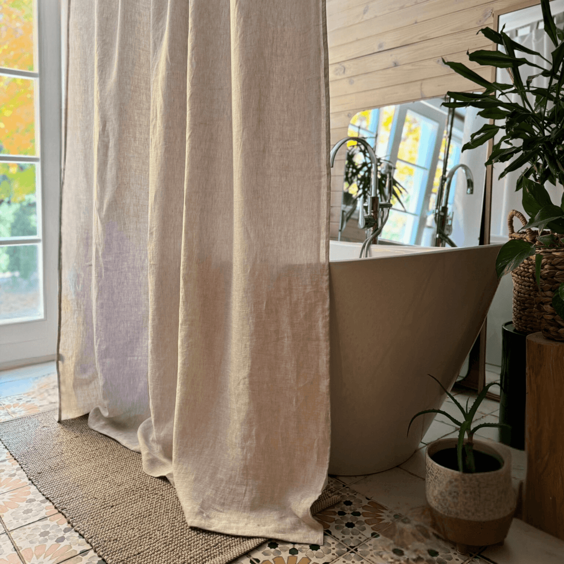 Natural linen shower curtain styled beside a freestanding bathtub with soft folds