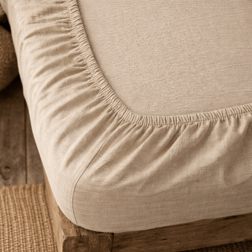 Linen fitted sheet in cream, close-up of corner elastic and fabric