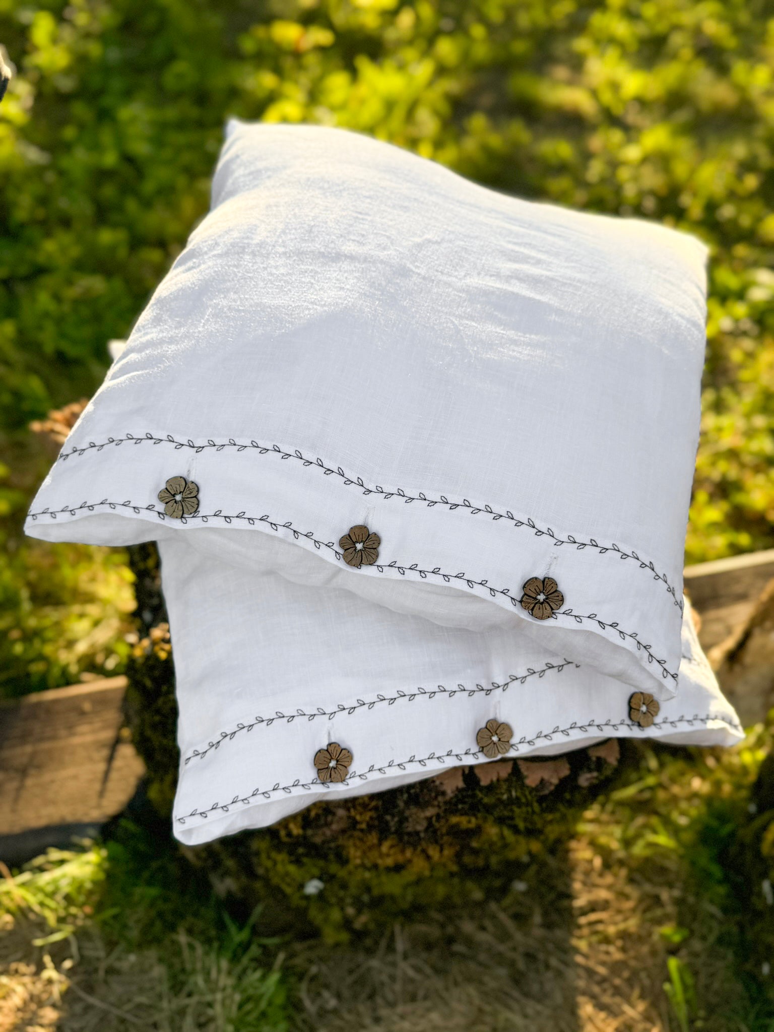 Black embroidered linen pillowcase on natural surface, embroidery detail