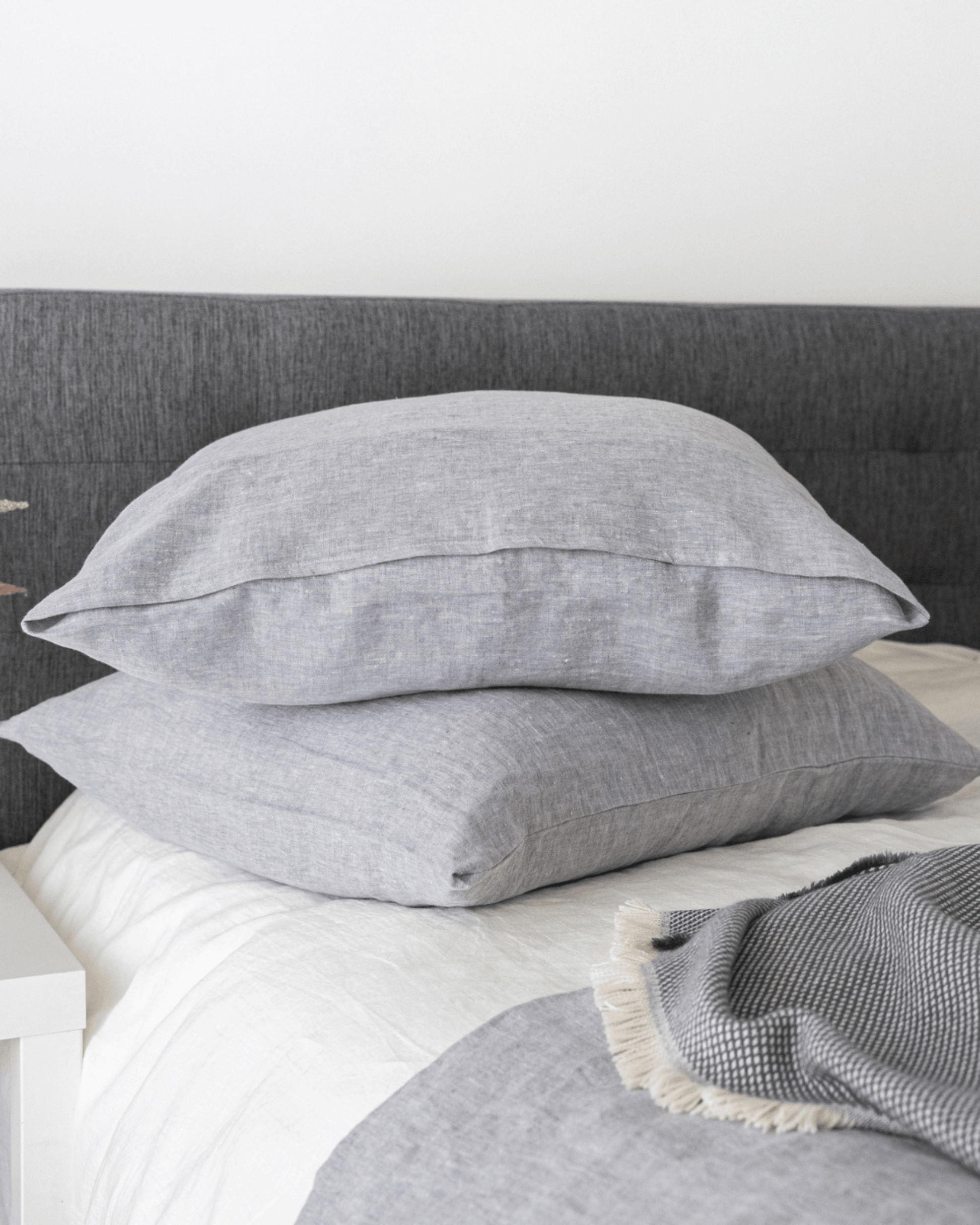 Minimalist linen pillowcase in natural tone on made bed, lifestyle shot