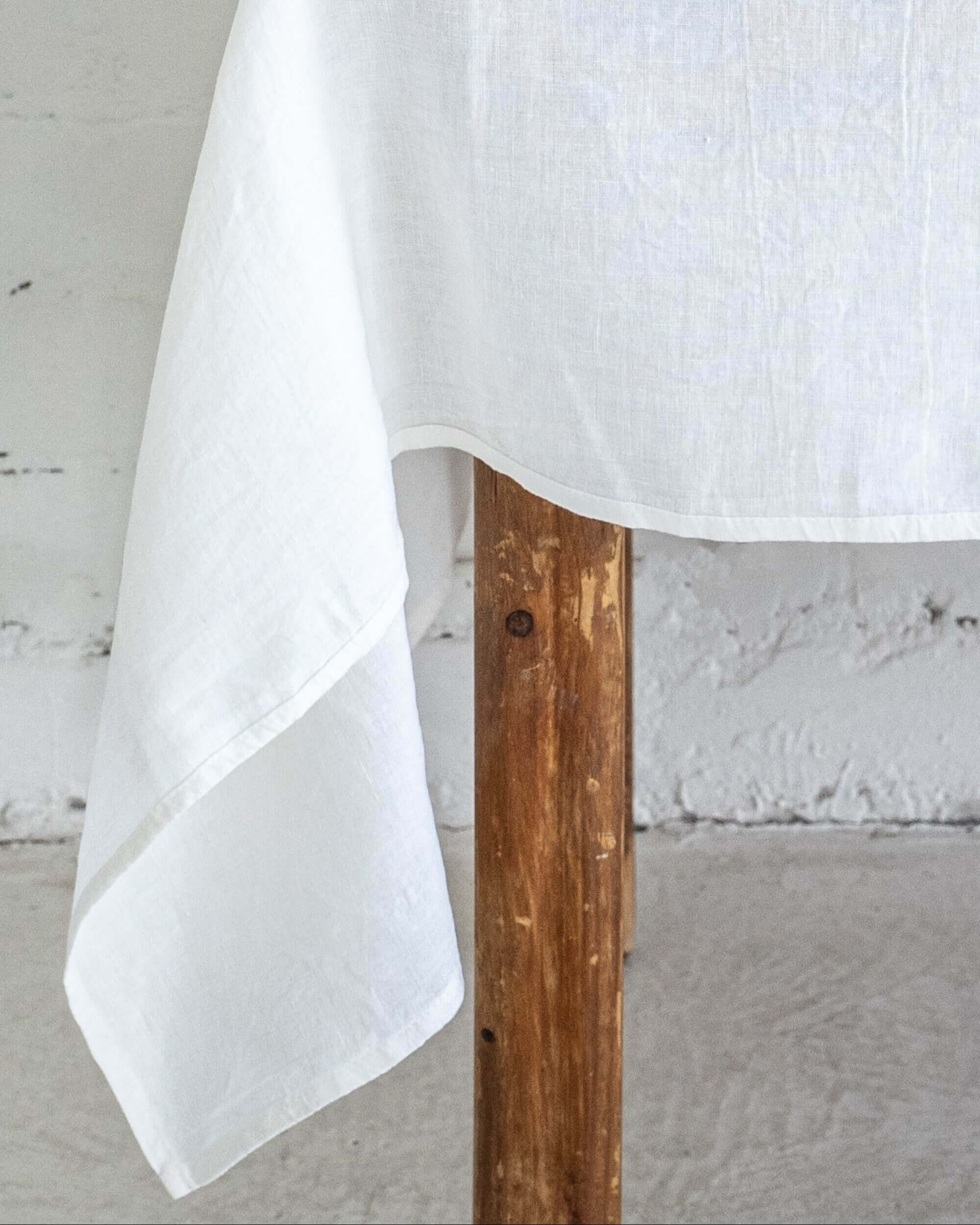 Linen tablecloth corner detail showing fabric drape over table edge
