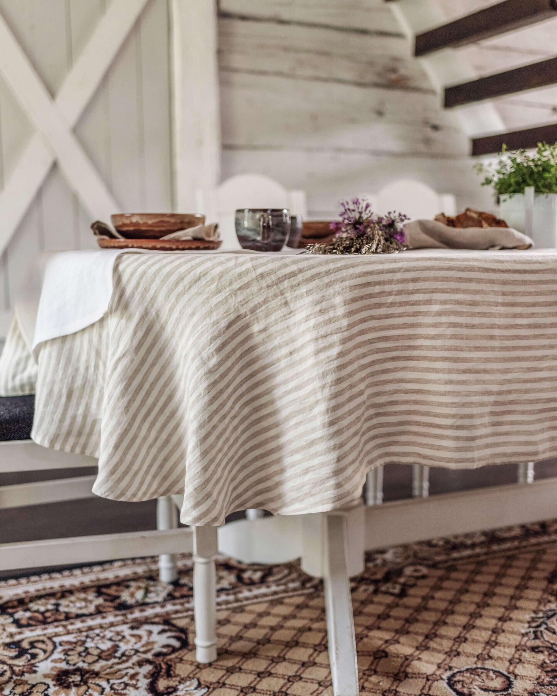Oval linen tablecloth on table with chairs, full setting view