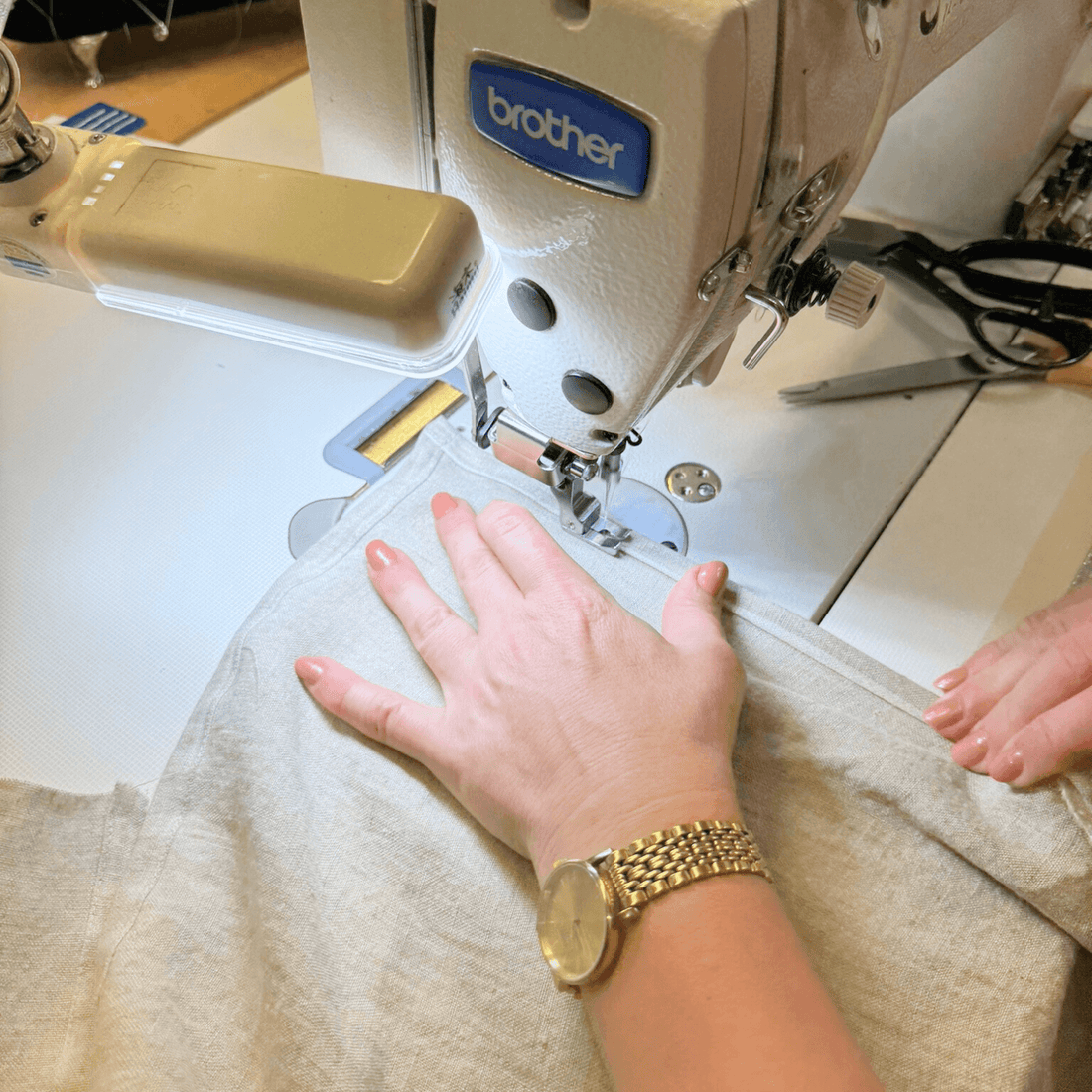 Hands sewing linen fabric in a small textile workshop