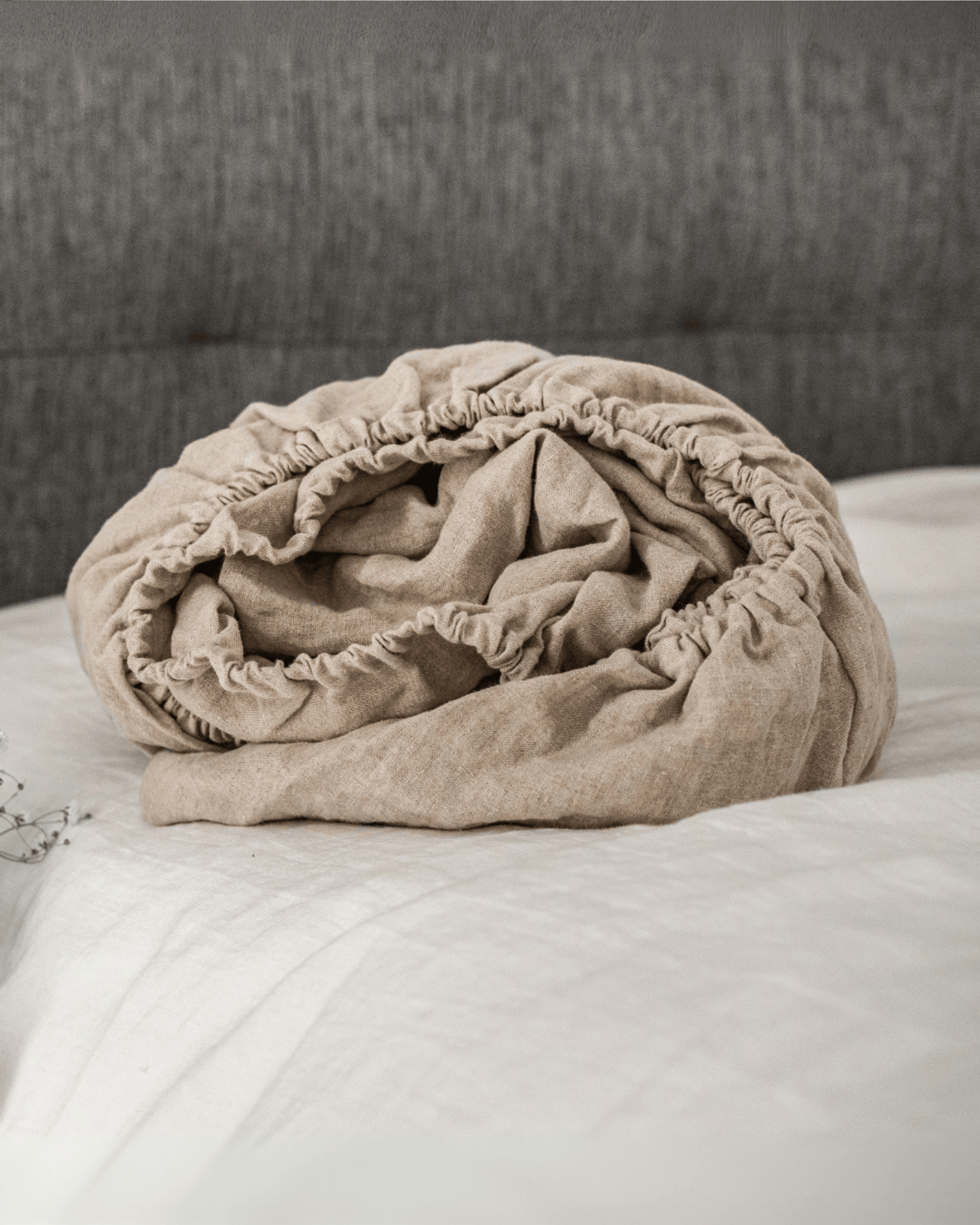 Linen fitted sheet on bed styled with linen blanket and floral vase