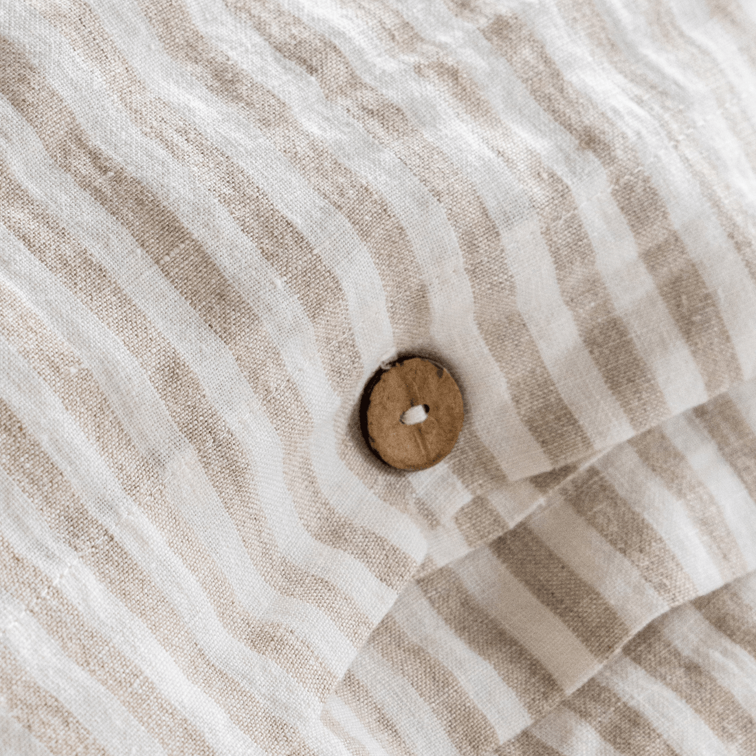 Close-up of striped linen fabric with a natural button closure detail
