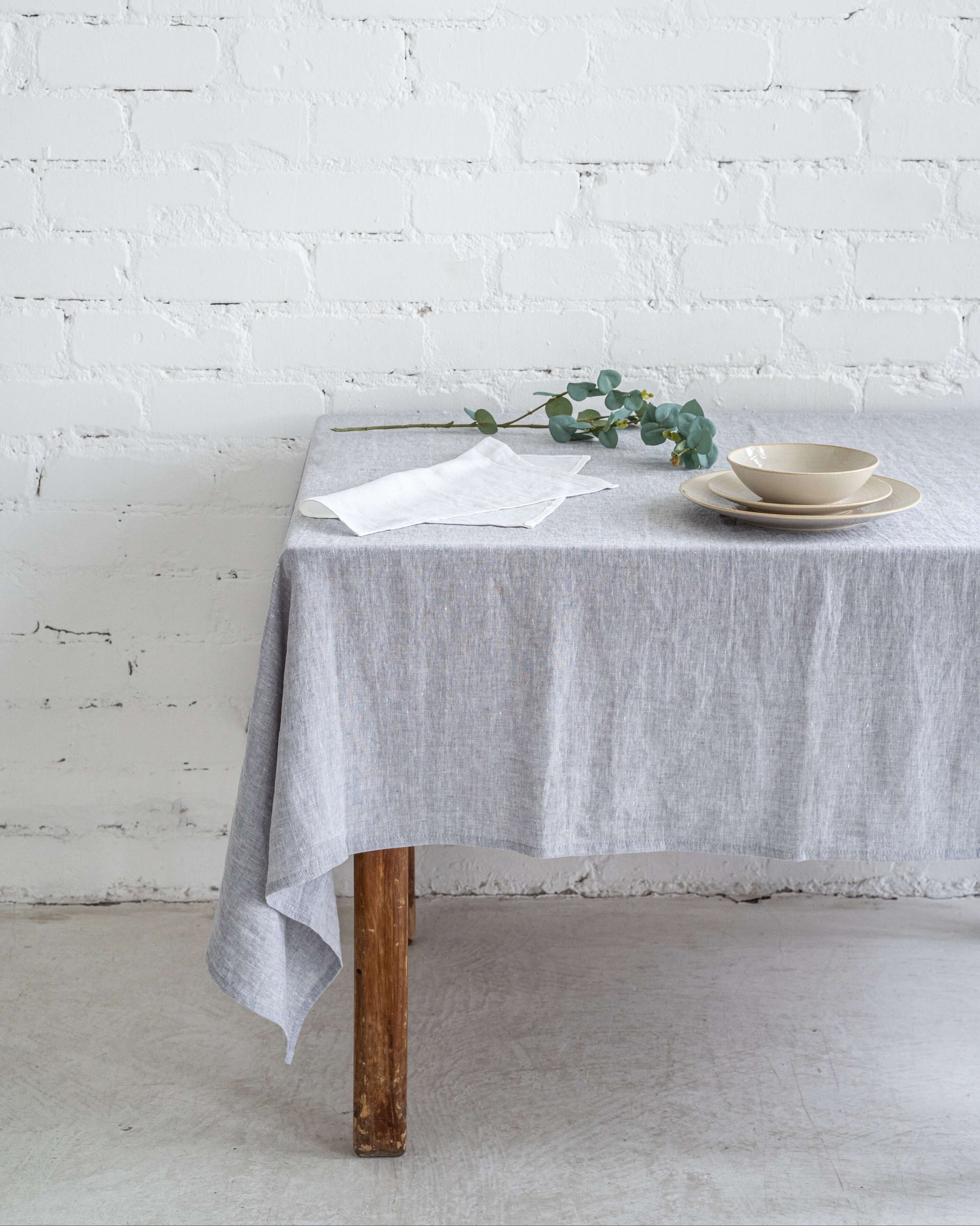 Linen tablecloth on round table with ceramic tableware