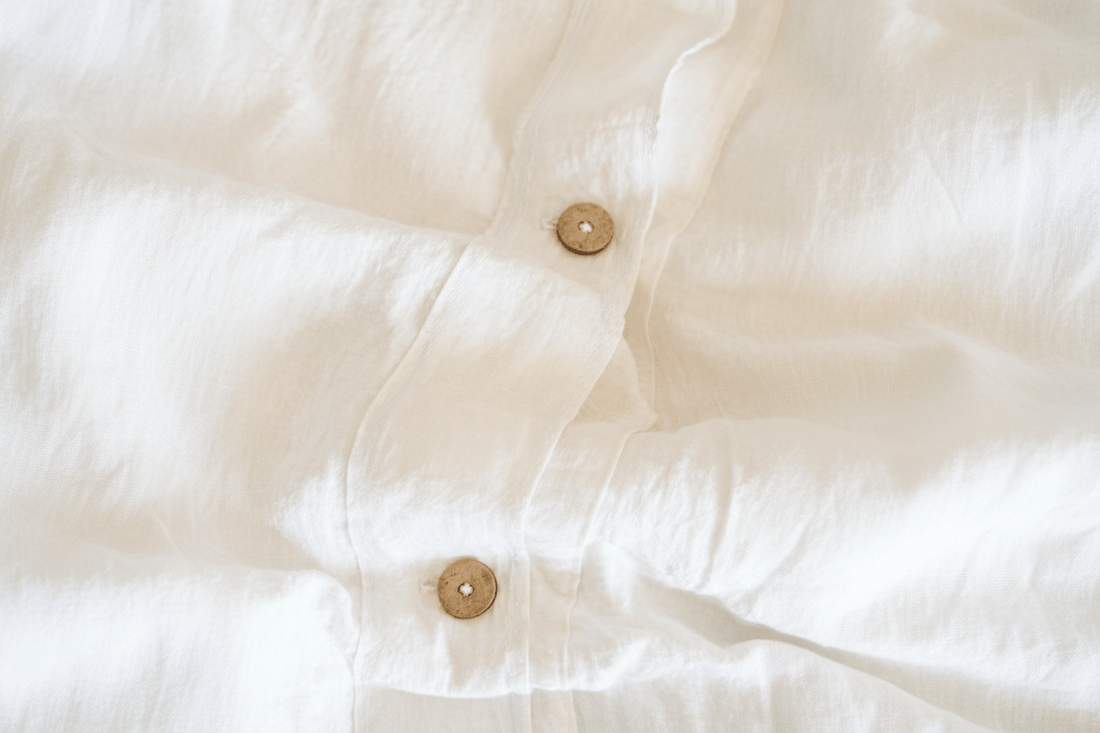 White linen bedding with visible button closure and soft natural wrinkles