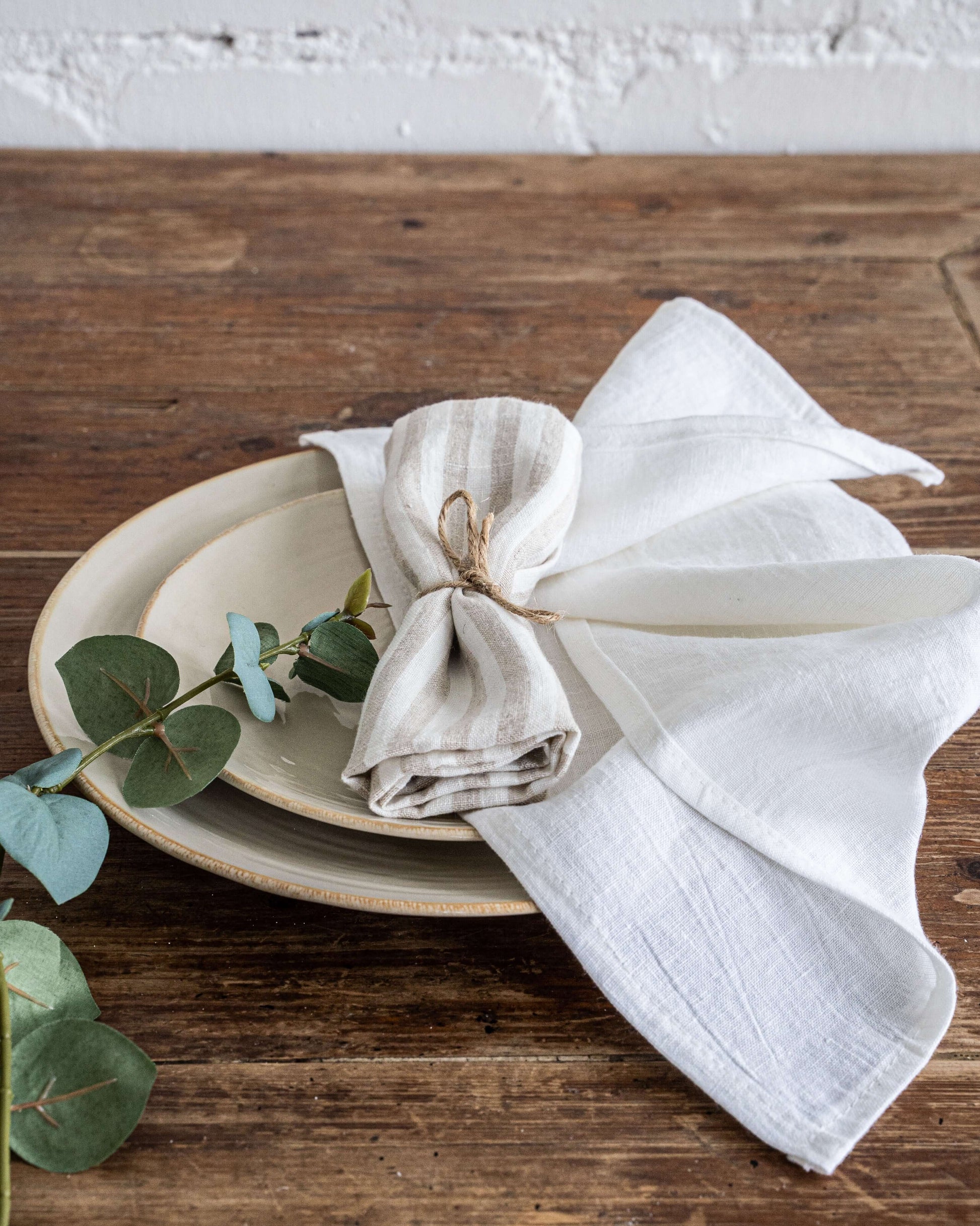 White linen napkin folded with fresh herbs, table styling