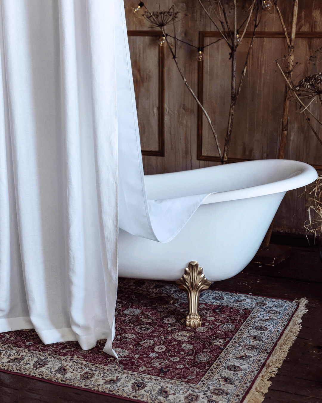 White shower curtain beside freestanding bathtub
