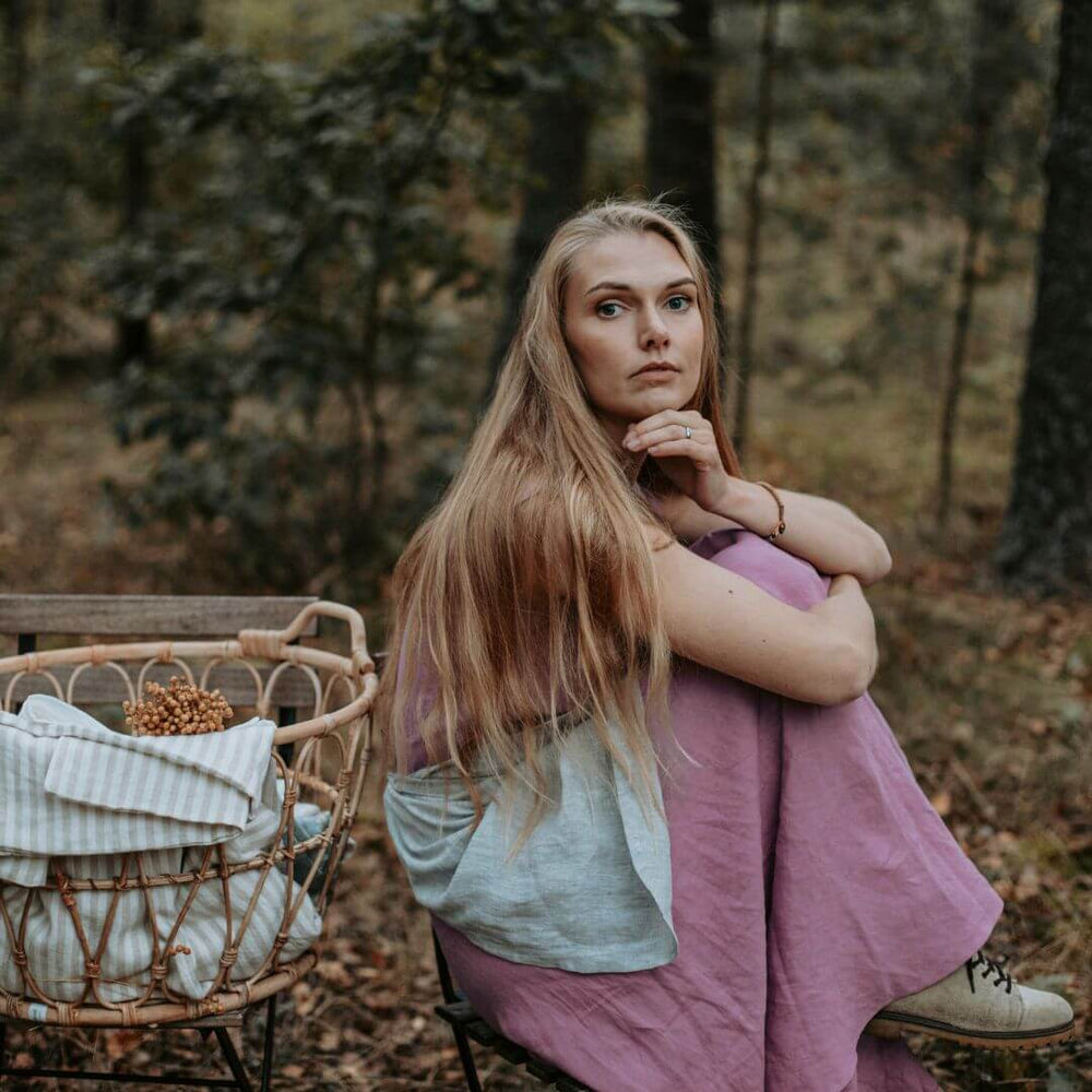Woman in dusty rose linen outfit holding woven basket outdoors
