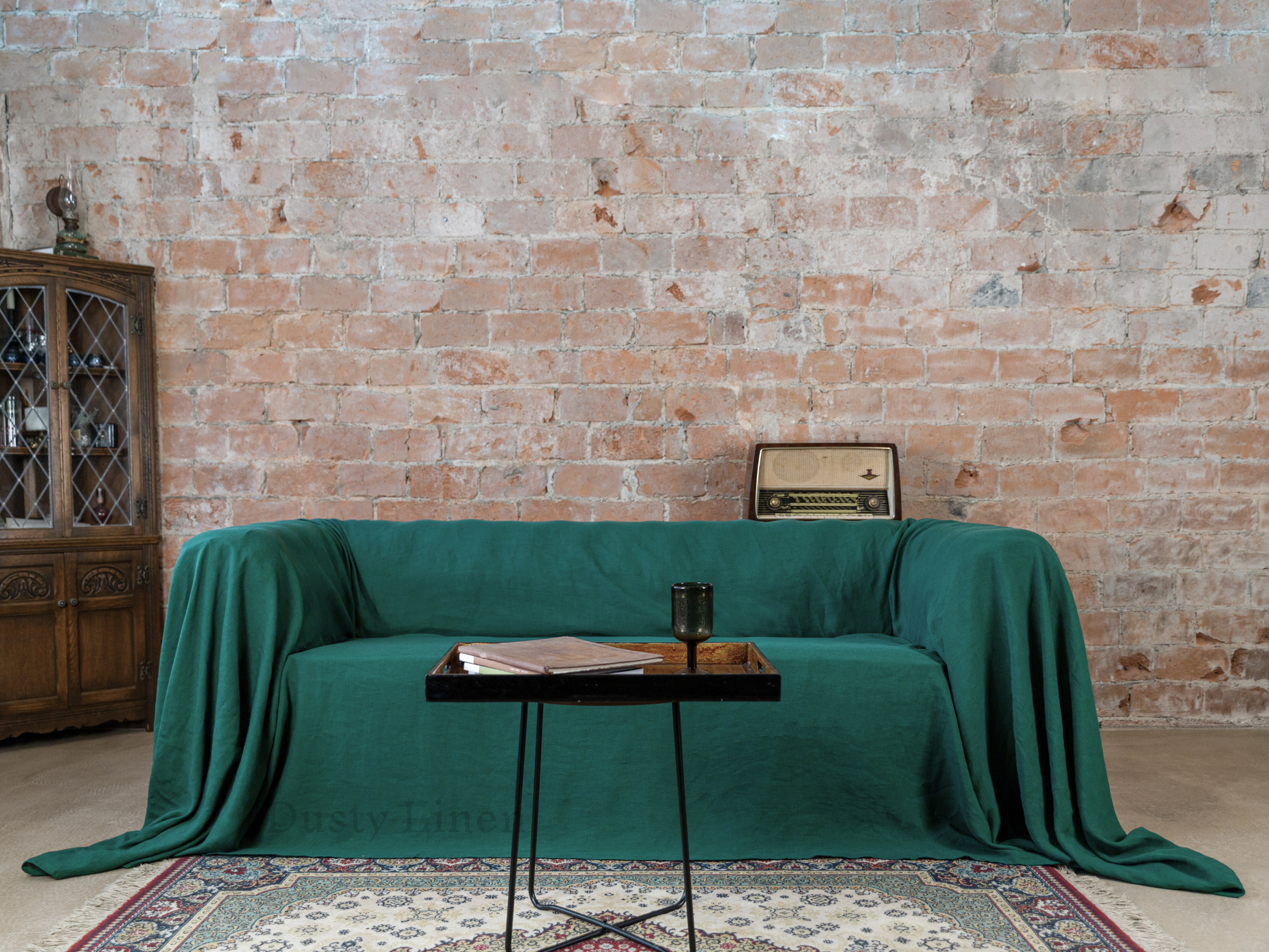 a living room with a green couch covered in a blanket