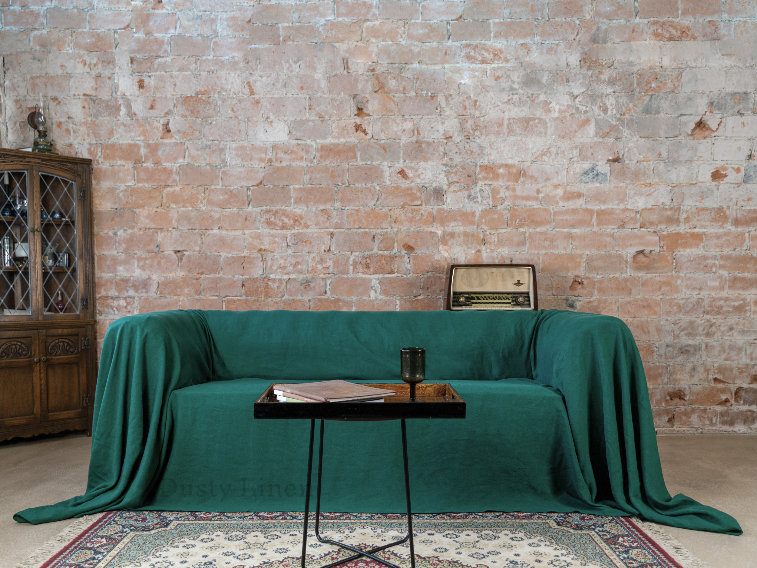 a living room with a green couch covered in a blanket