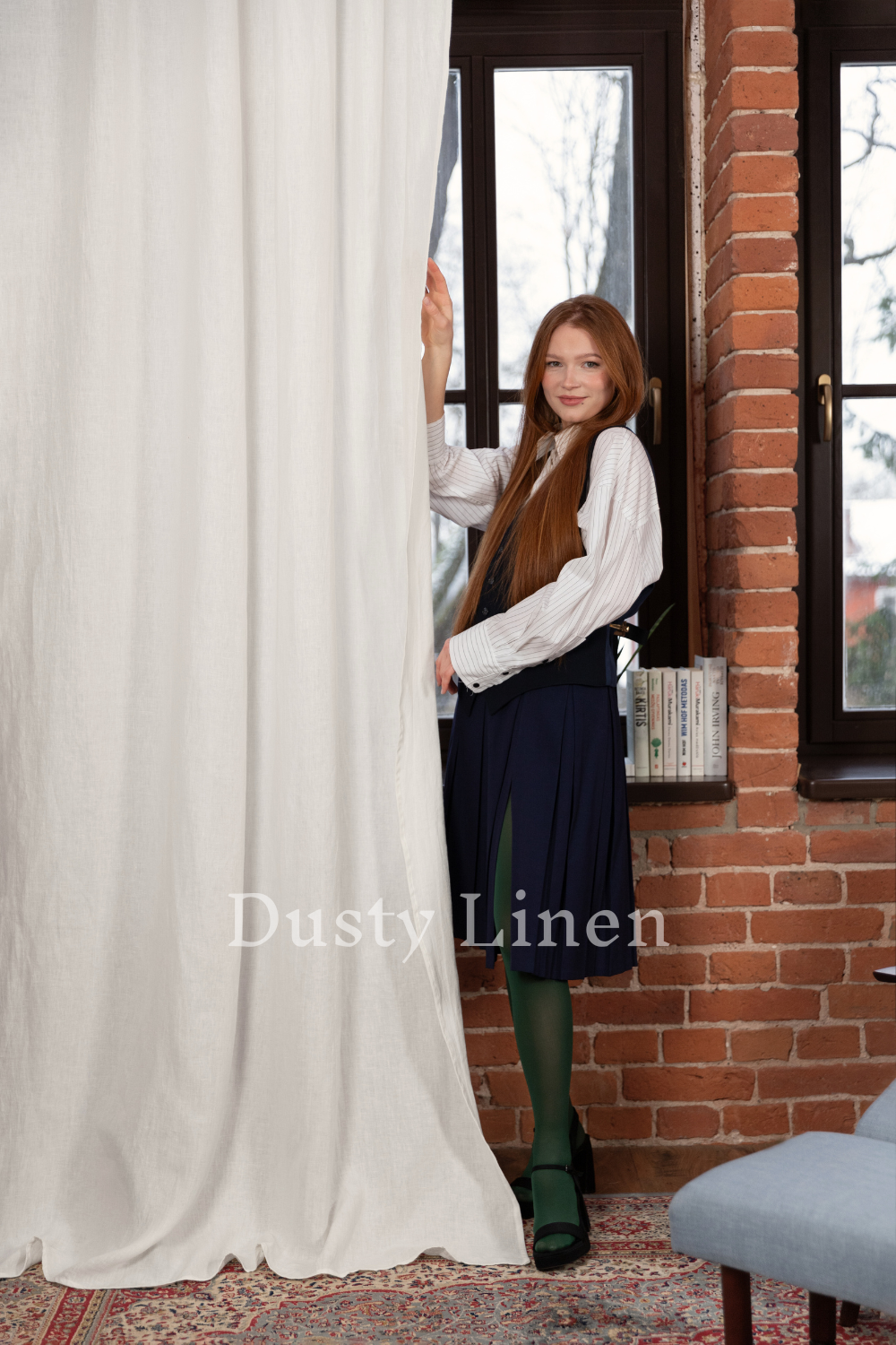 a woman standing behind a curtain in front of a window