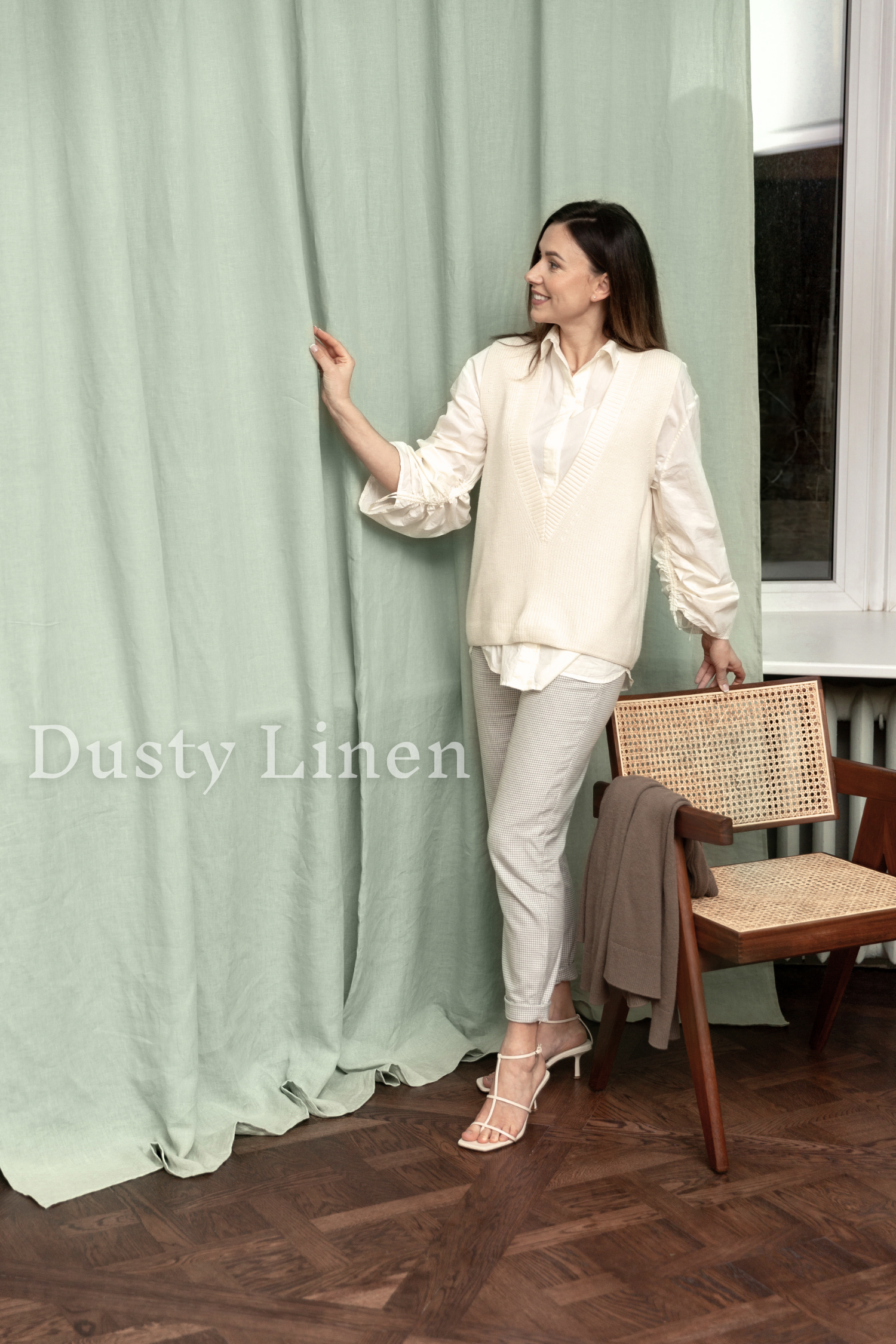 a woman standing next to a chair in front of a curtain