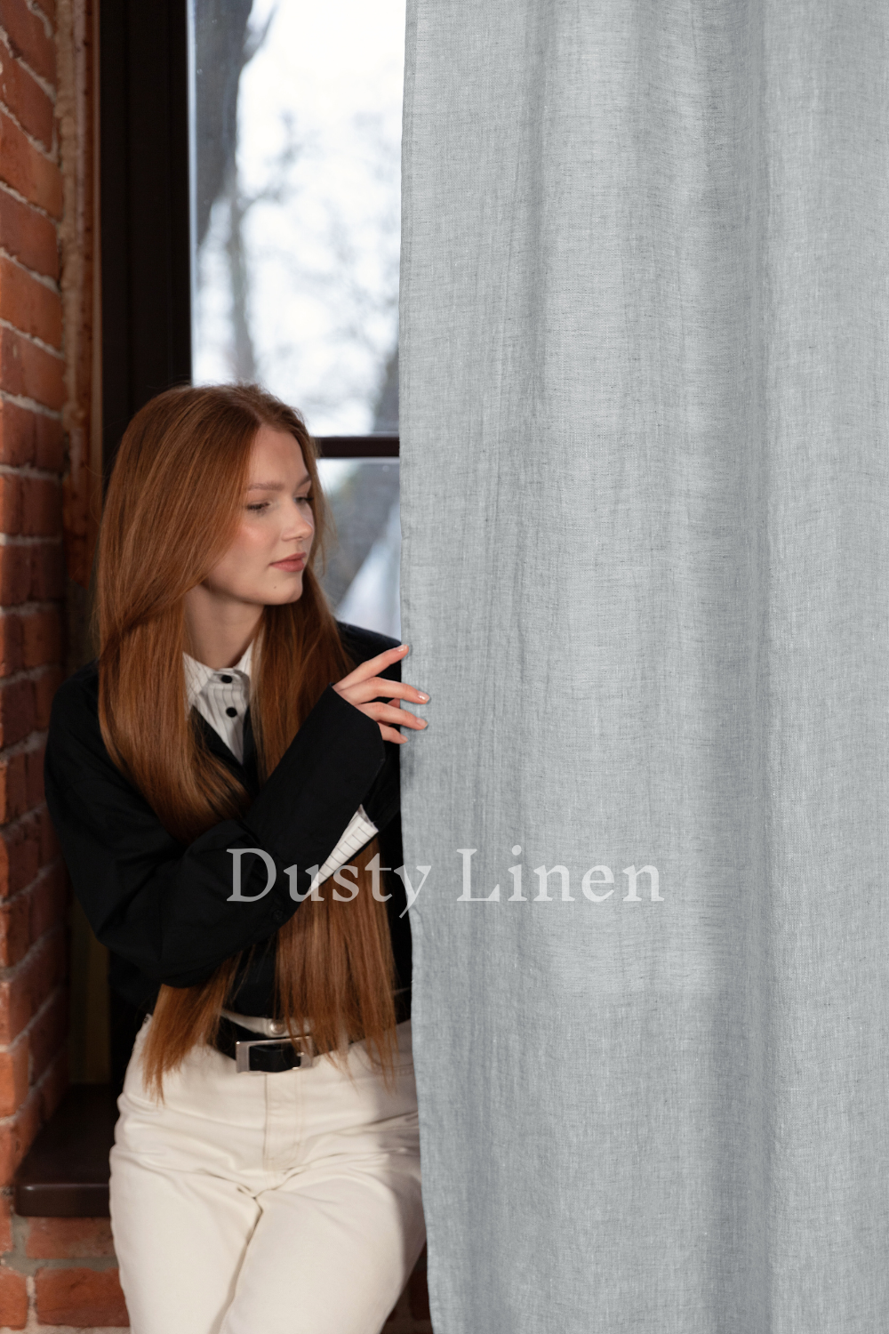 a woman with long red hair leaning against a curtain