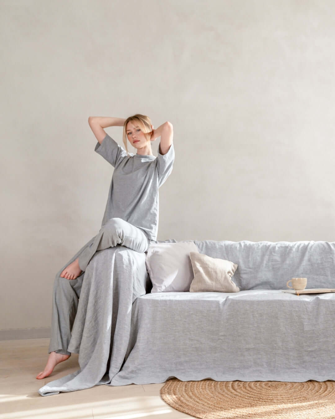 a couch covered with a grey linen blanket in a living room. Luxury couch cover