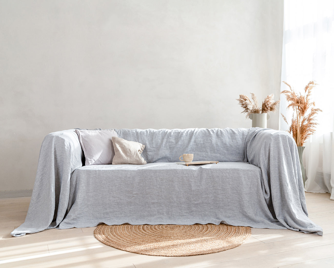 a couch covered with a grey linen blanket in a living room. Luxury couch cover