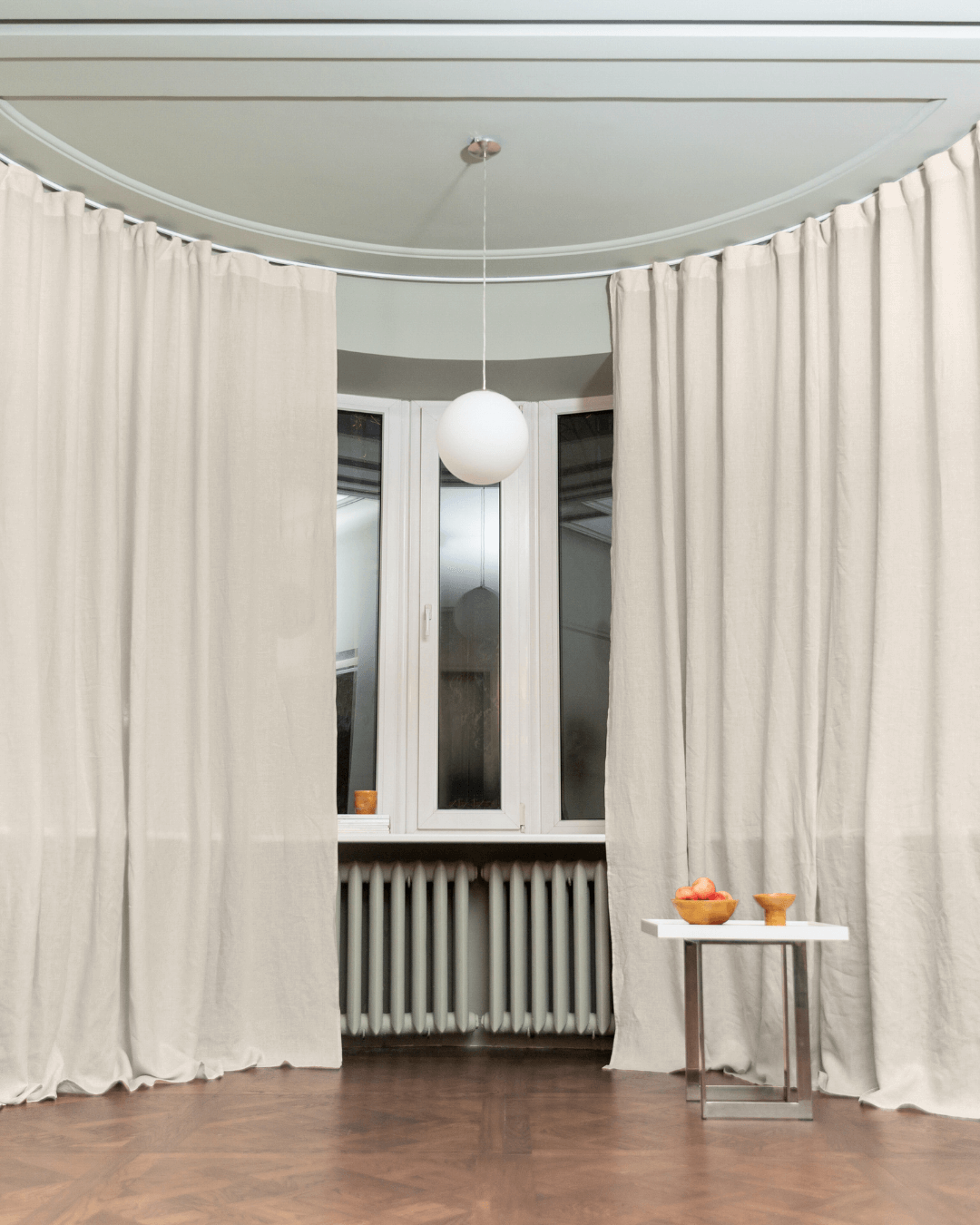 a room with a white curtain and a table with fruit on it