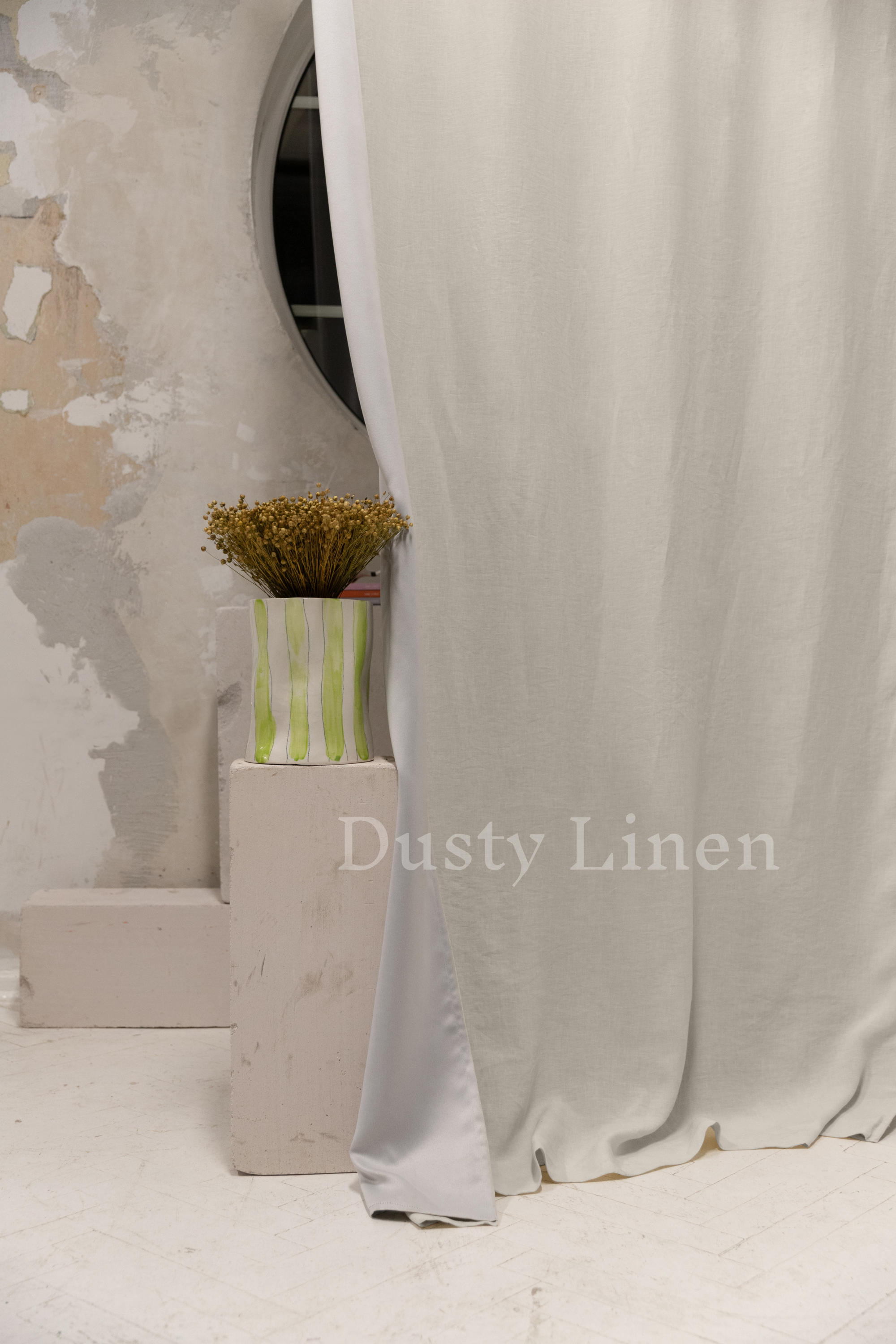 a vase with a flower in it next to a curtain