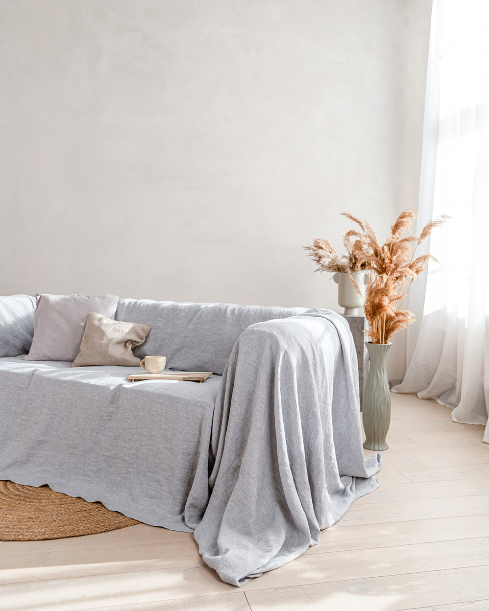 a living room with a couch covered in a light gray linen blanket