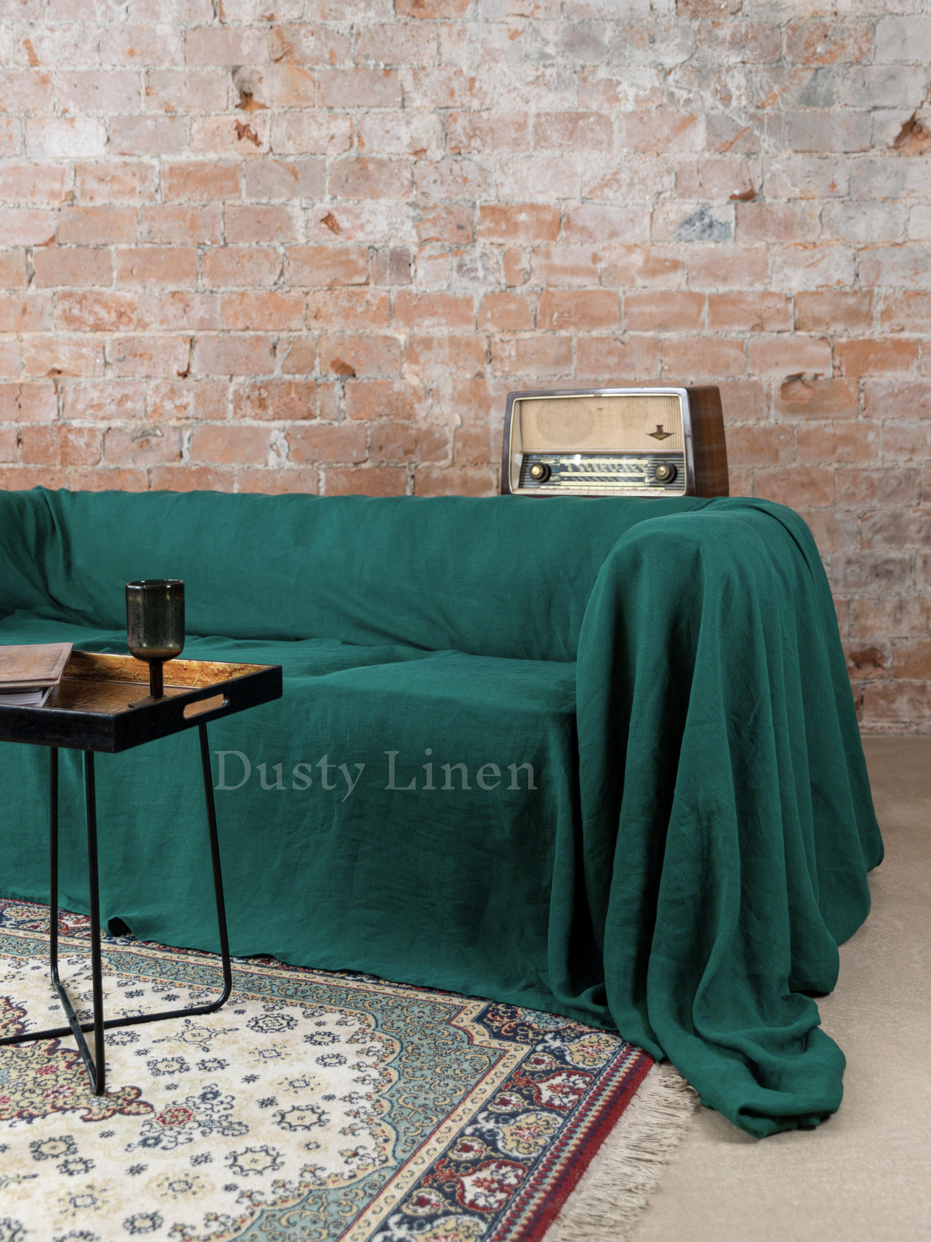 a couch covered in a green blanket next to a table