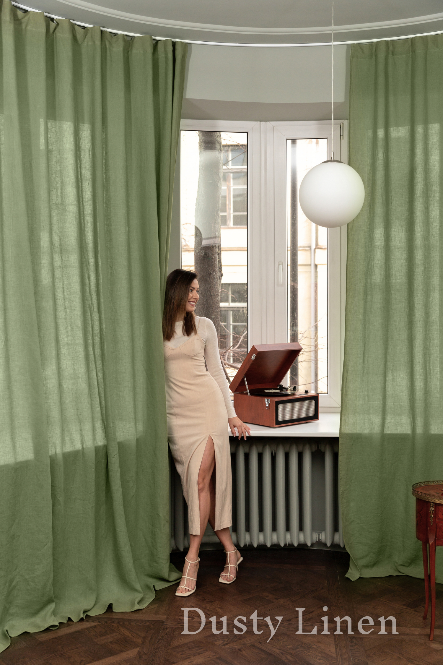 a woman standing in front of a window next to a radiator