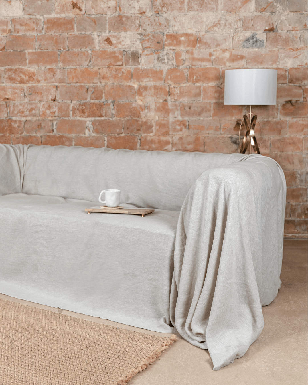 a couch covered in a blanket next to a lamp