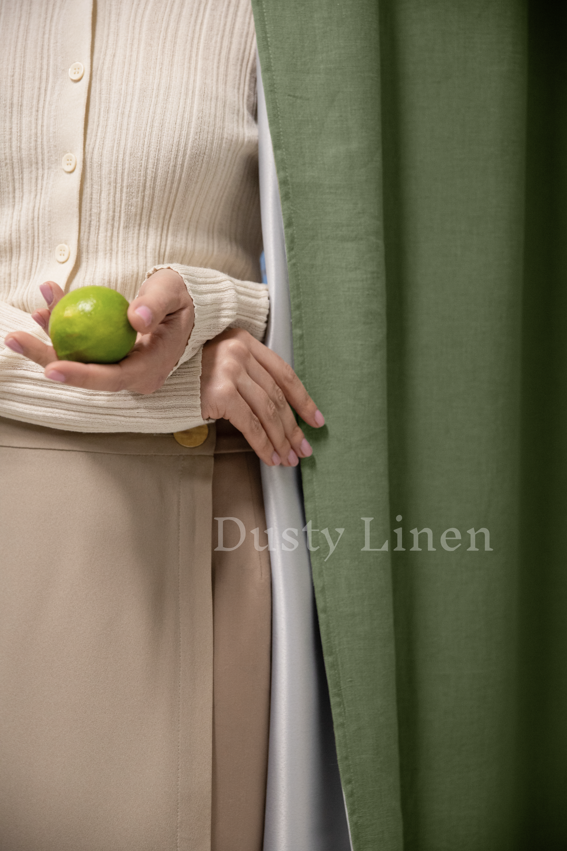 a woman holding a green apple behind a curtain