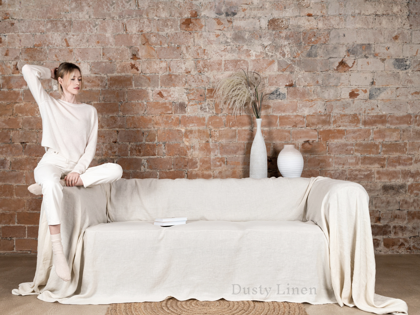 a woman sitting on a couch in front of a brick wall