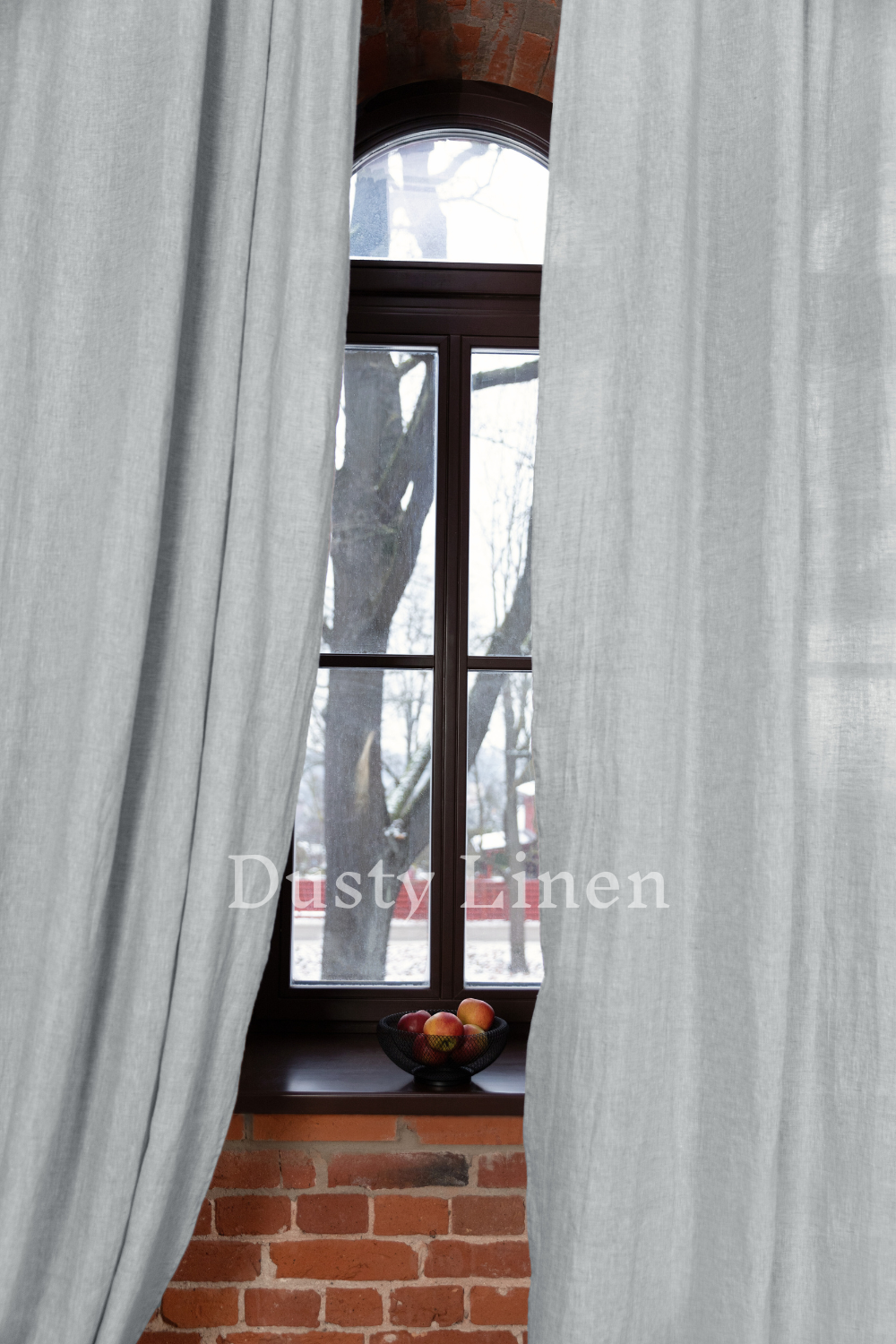 a window with a curtain and a bowl of fruit in front of it