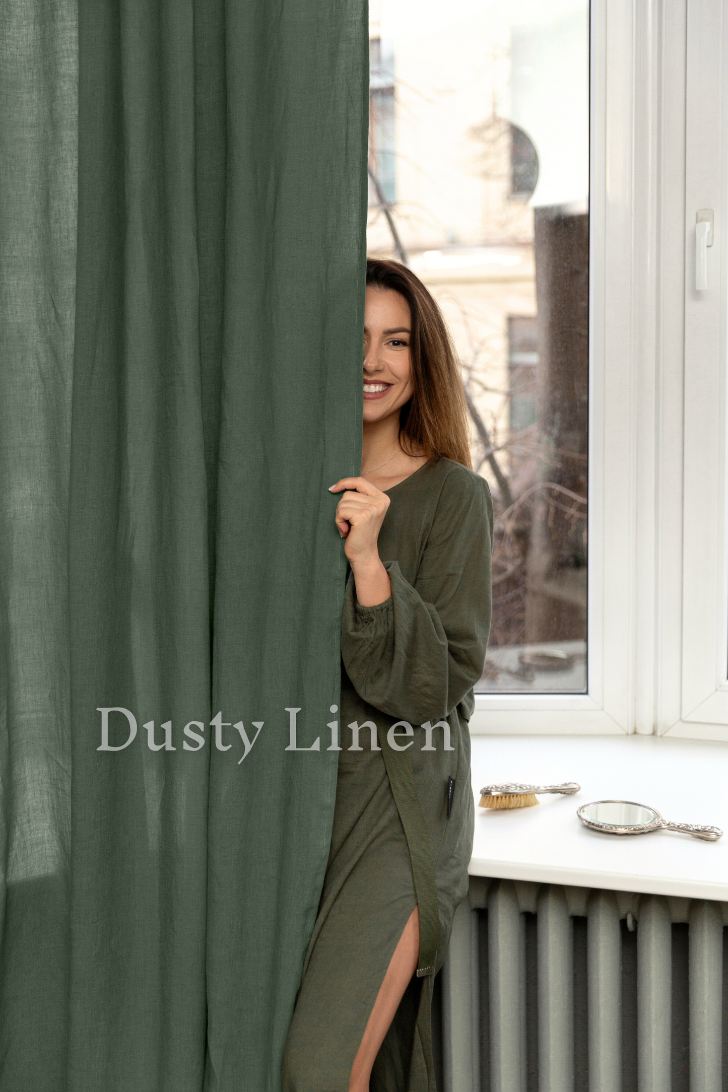 a woman standing behind a curtain holding a cell phone