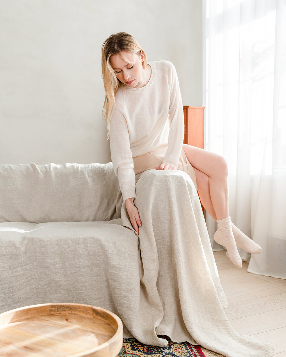 a woman sitting on a couch in a natural light couch cover in a room