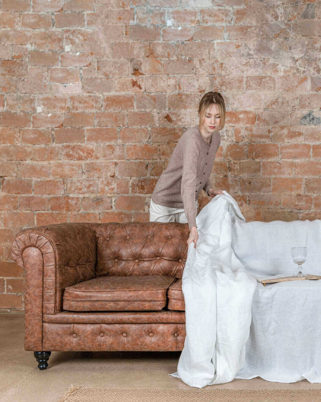 Woman standing beside sofa with white linen couch cover, size reference
