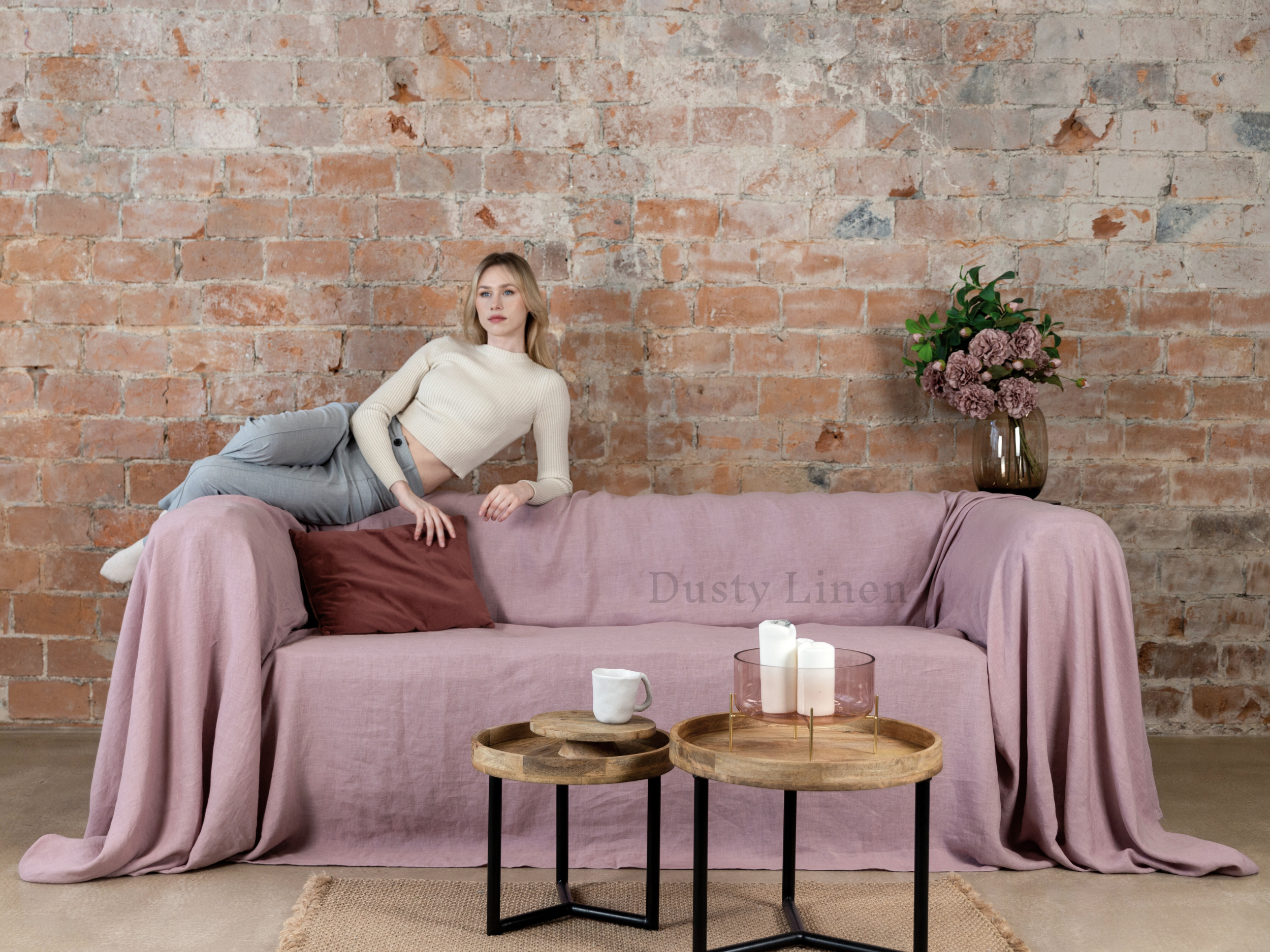 a woman sitting on a couch with a pink blanket