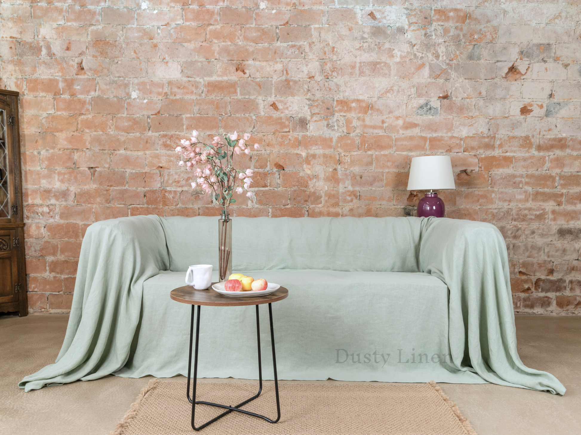 a couch covered with a blanket and a vase with flowers