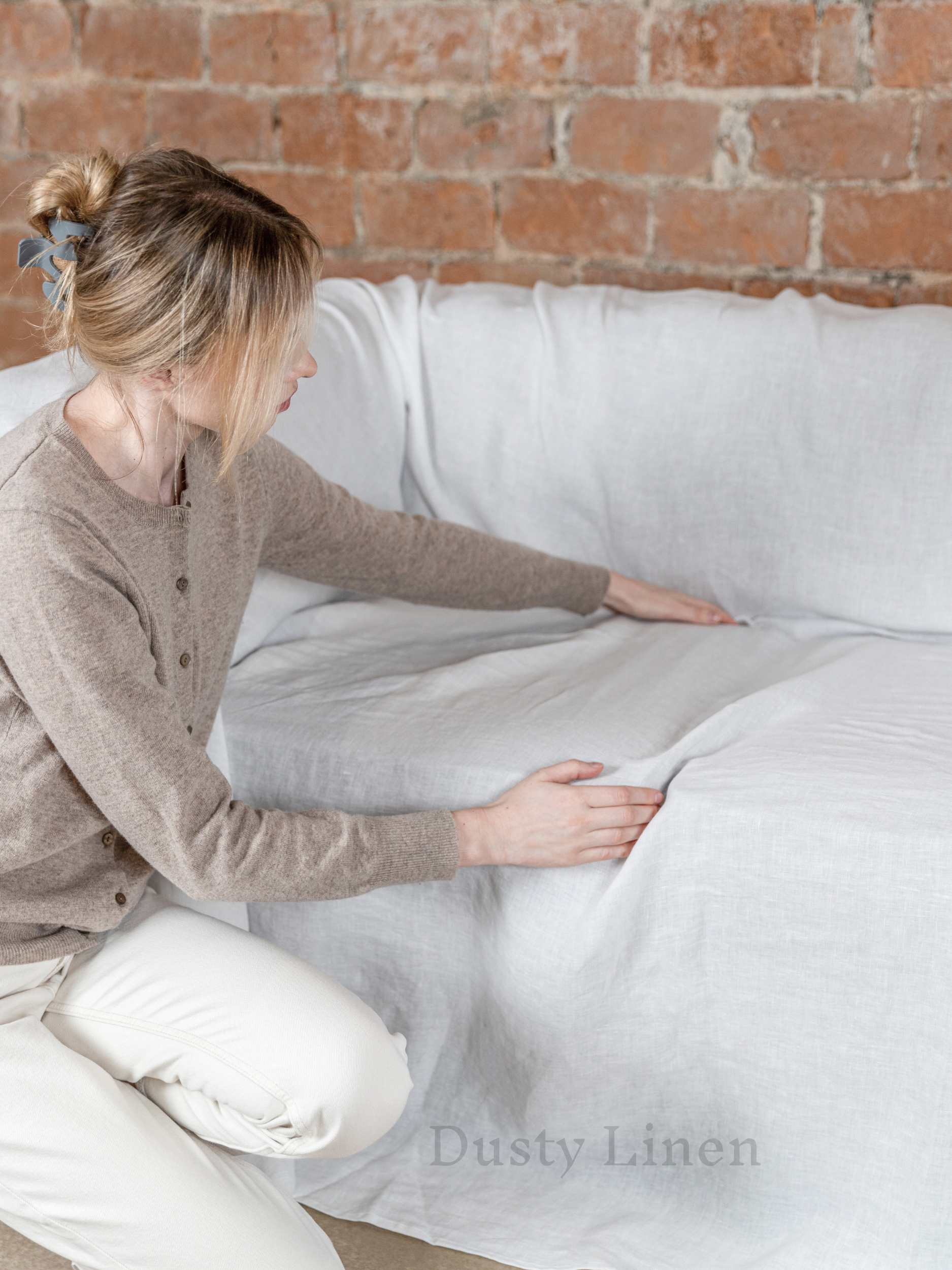 a woman sitting on a couch with a white pillow