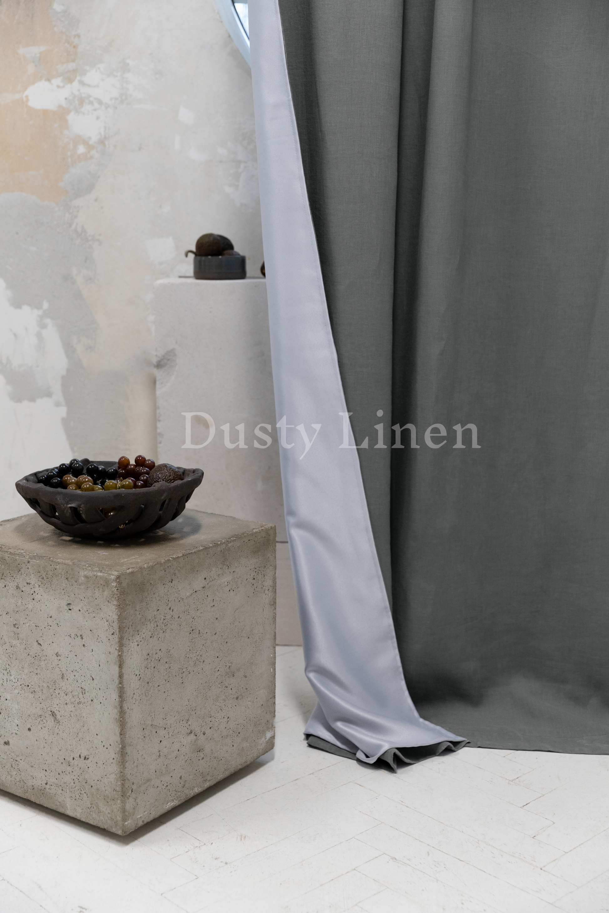 a bowl sitting on top of a cement block next to a curtain